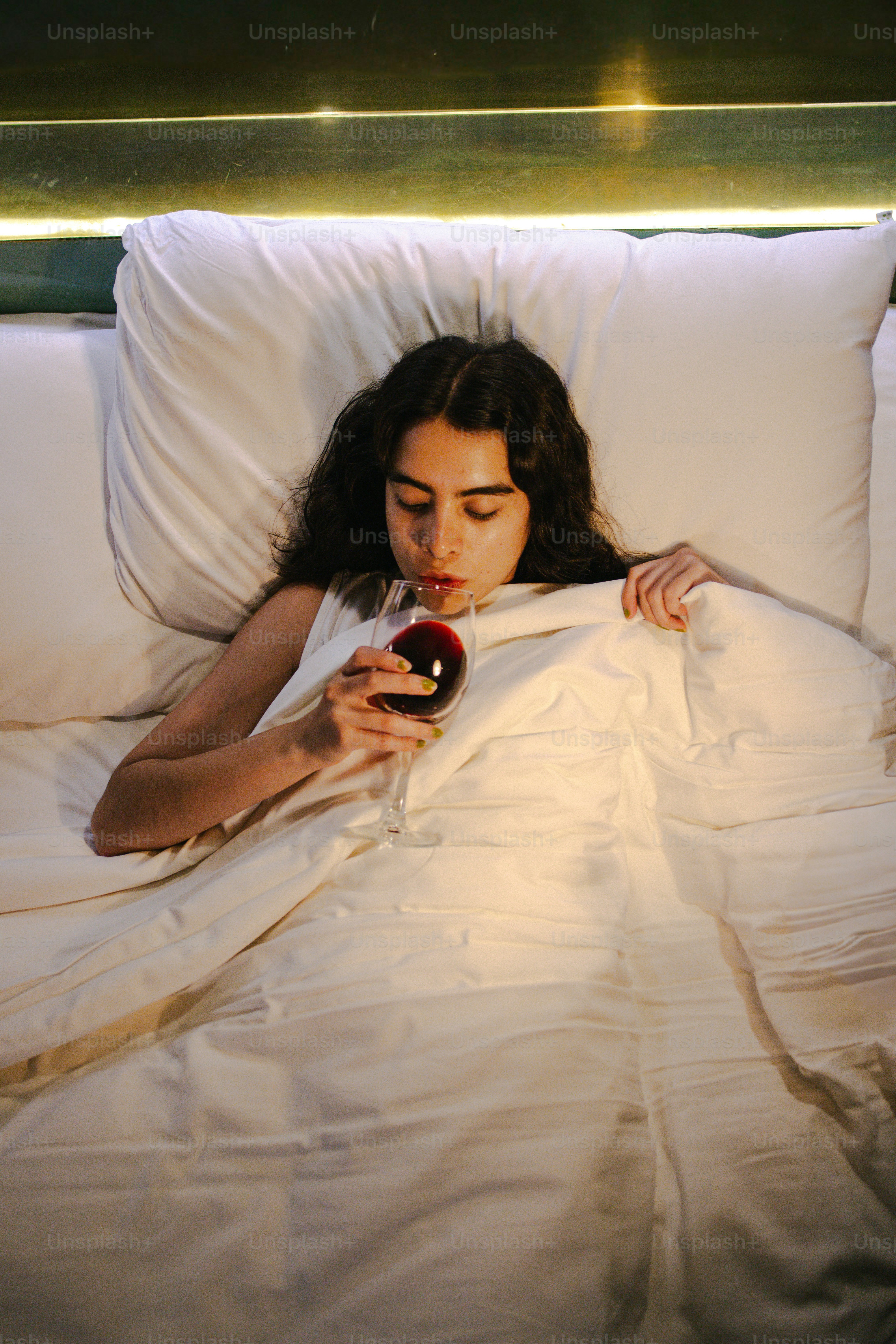 Donna a letto che beve vino rosso