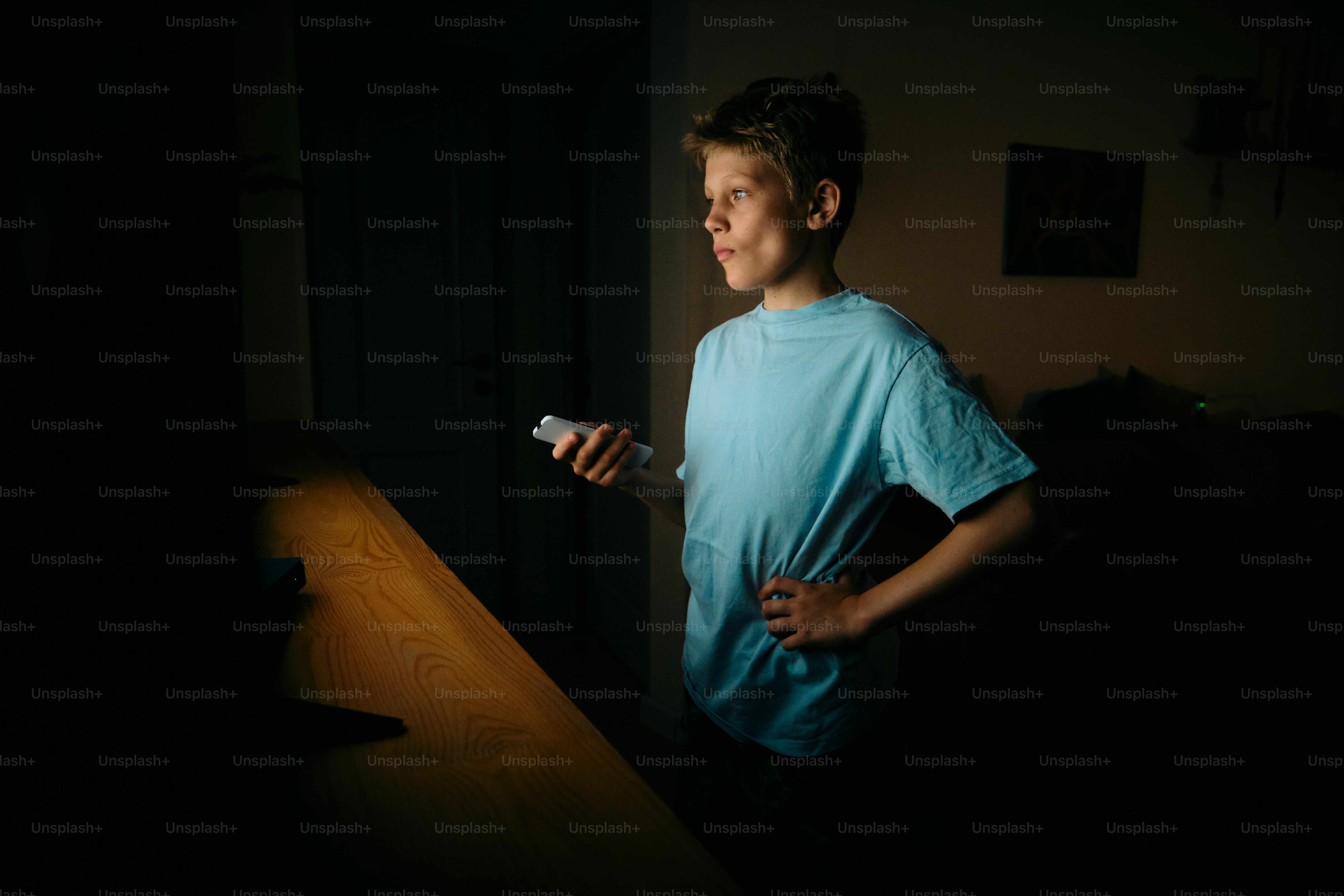 Young boy illuminated by phone screen in dark room photo – Technology ...