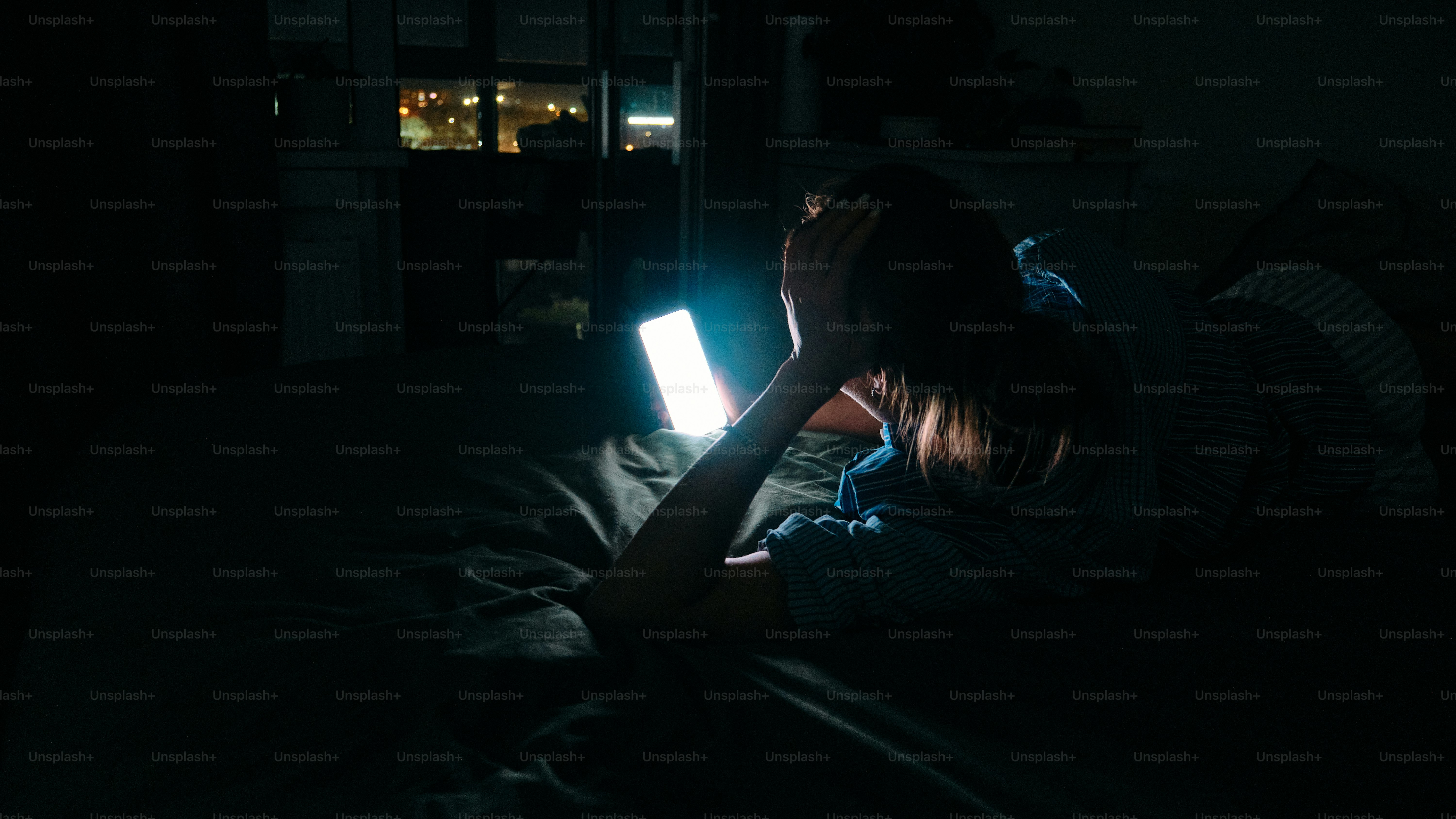 Person using a glowing smartphone in a dark room.