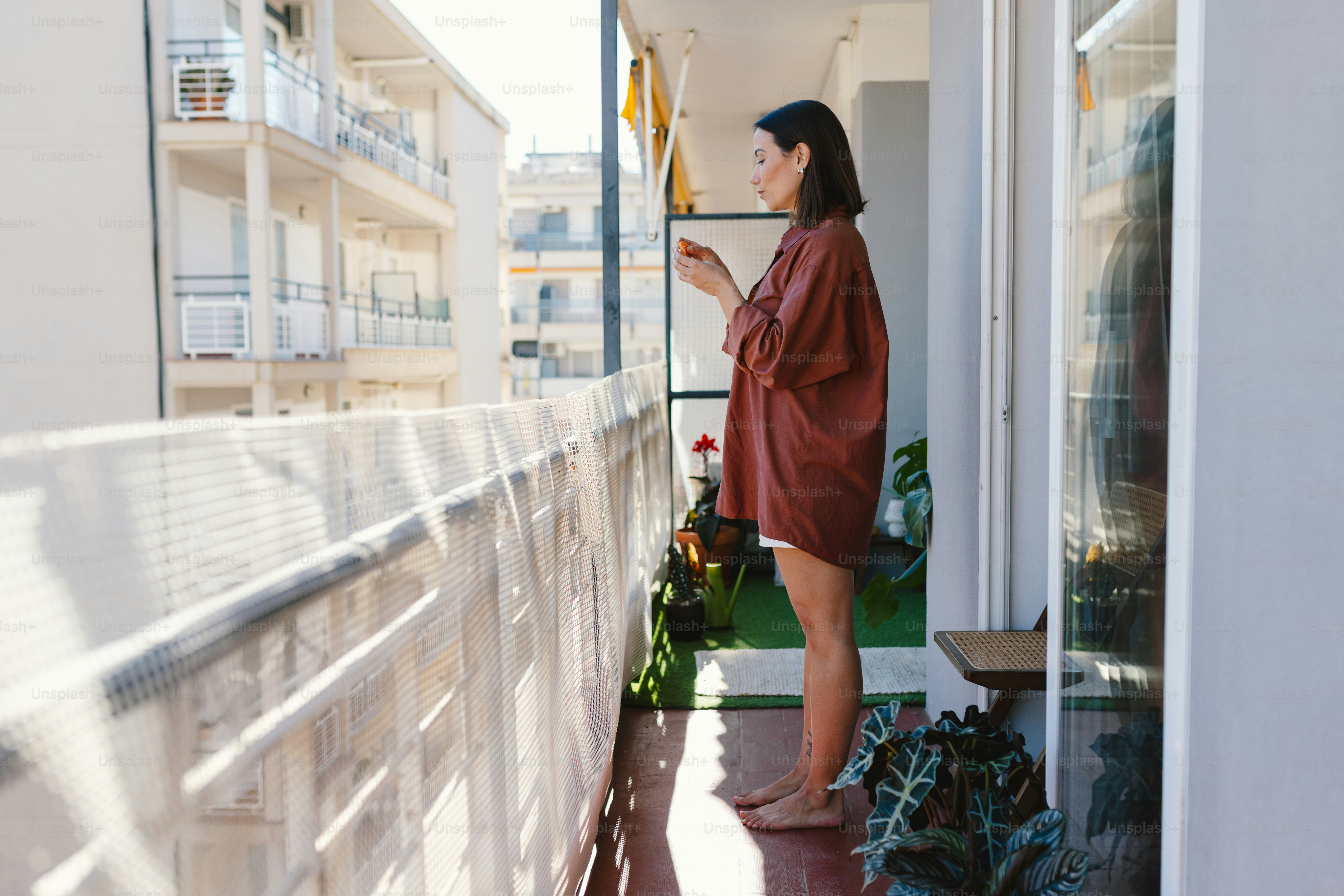 Woman standing on a balcony looking at phone.