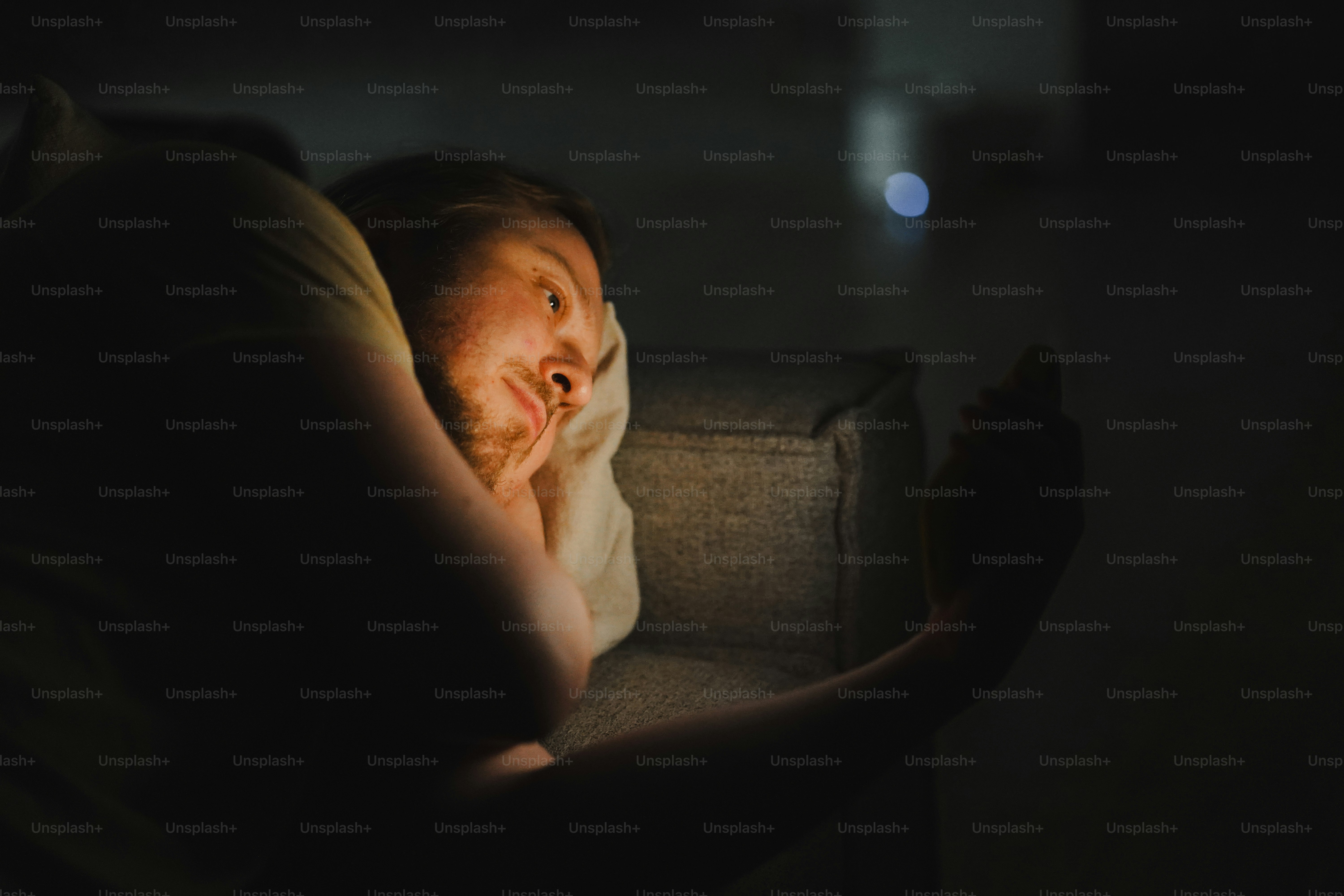 暗闇の中で電話の画面に照らされた人物。