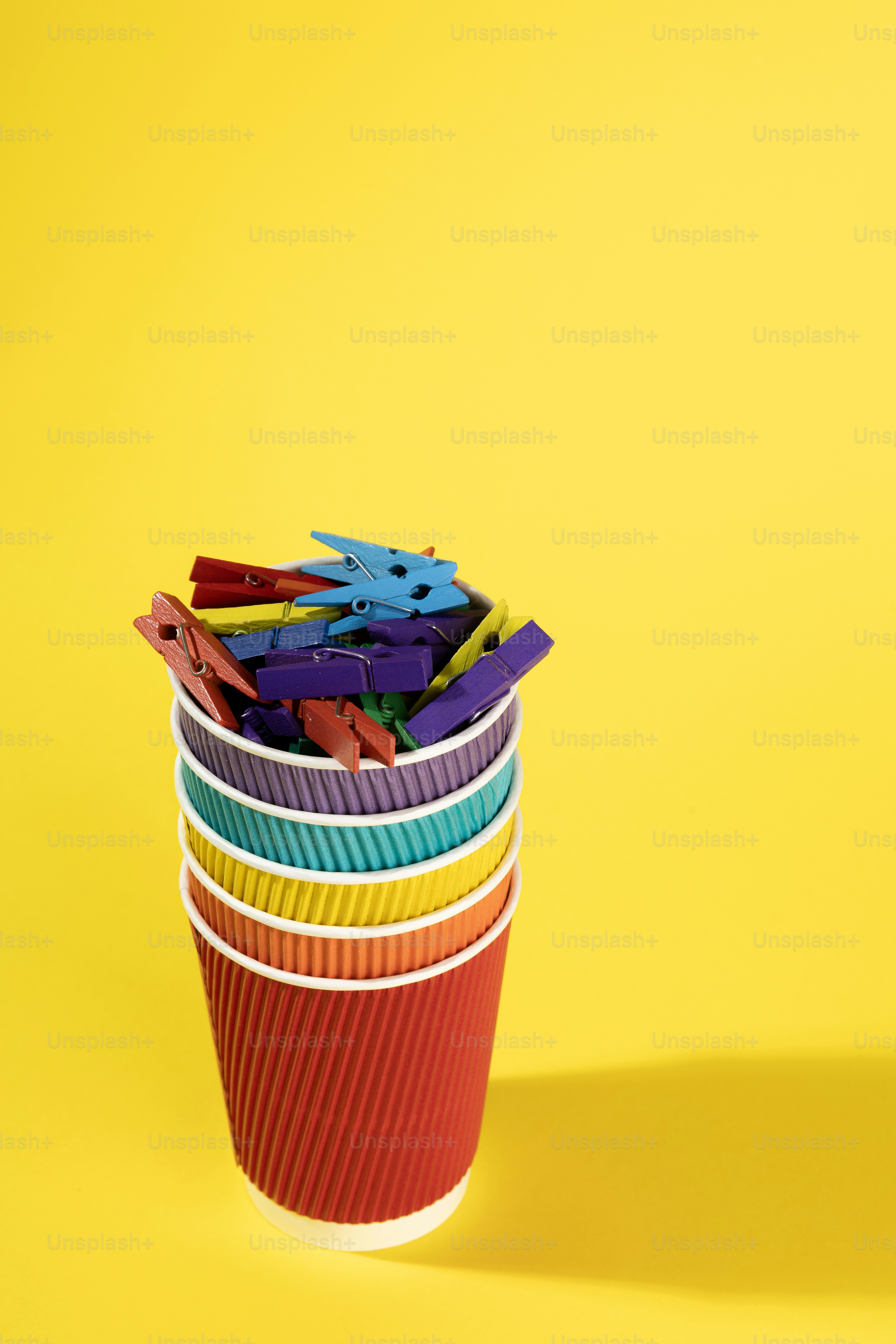 Stack of colorful cups filled with clothespins