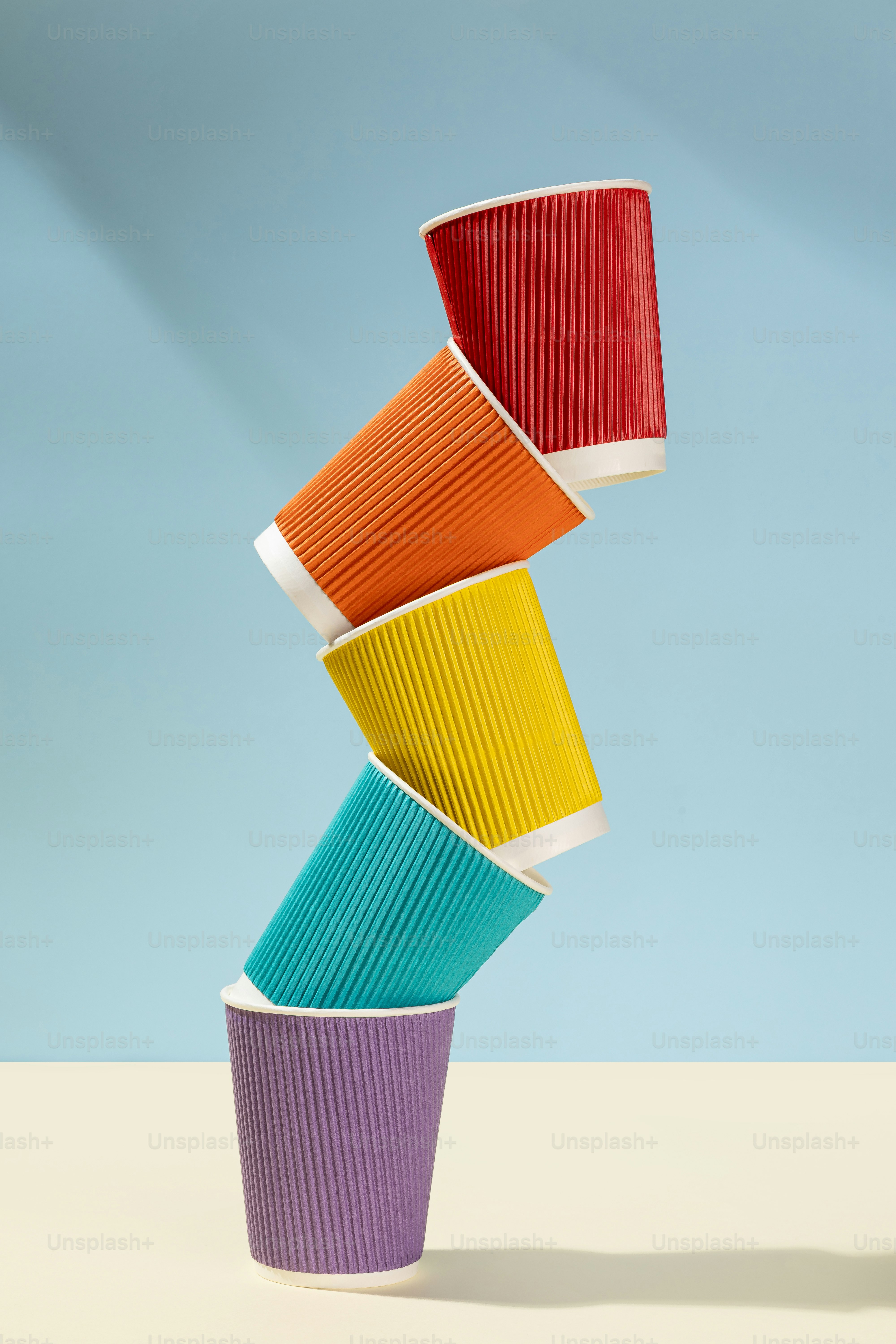Stack of colorful ribbed paper cups on a light background. photo ...
