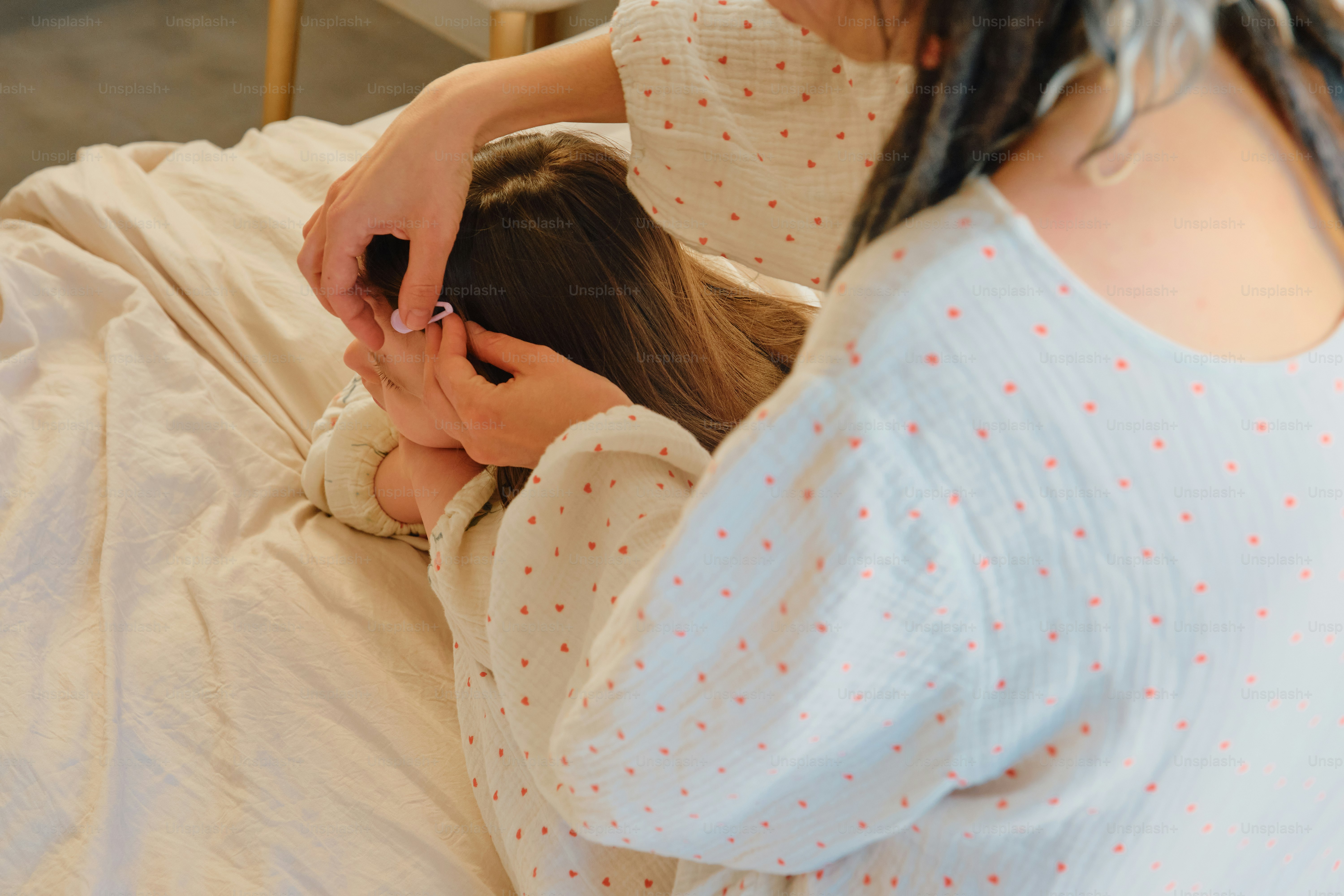 Mother styling her daughter's hair on the bed