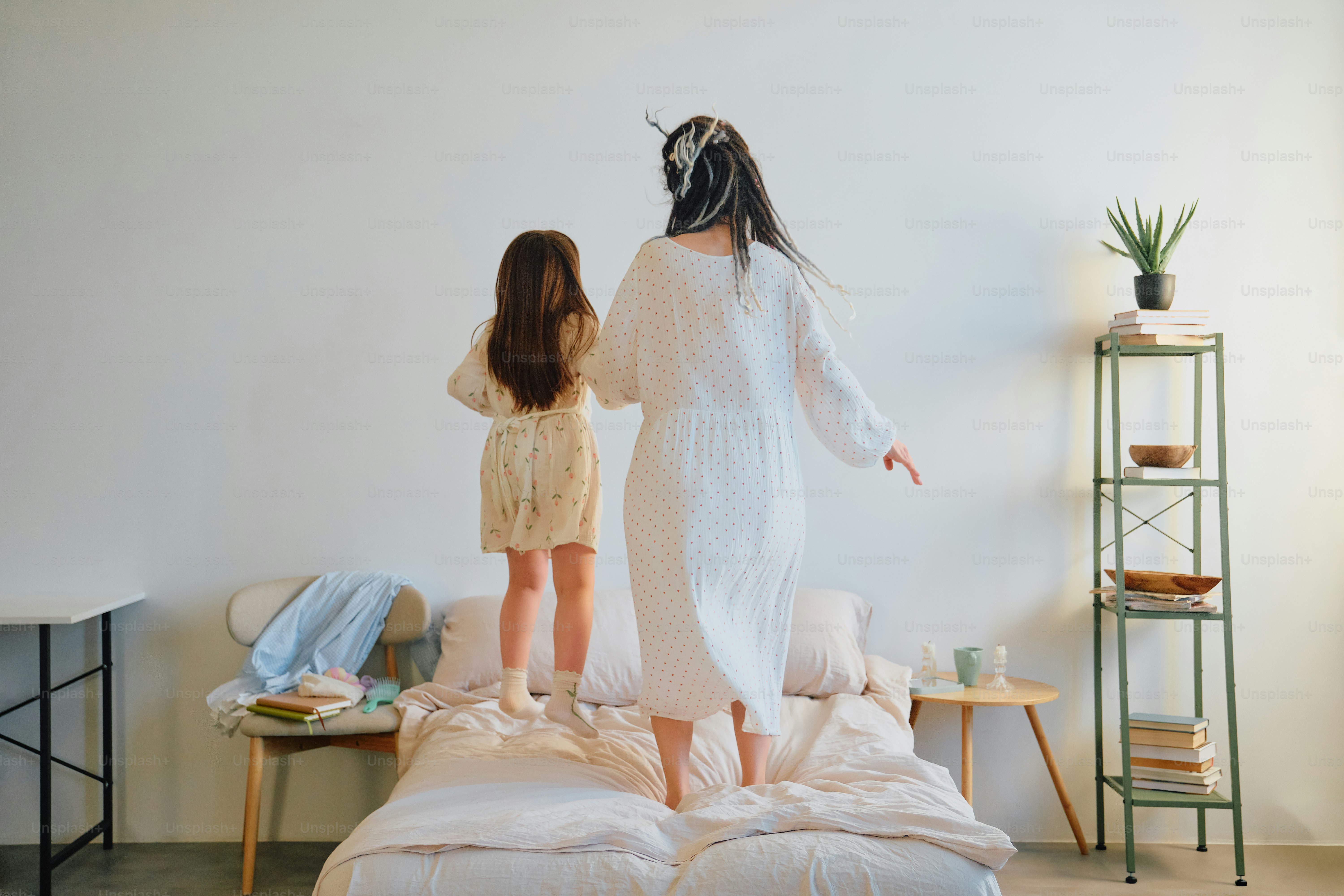 Mother and daughter jumping on a bed