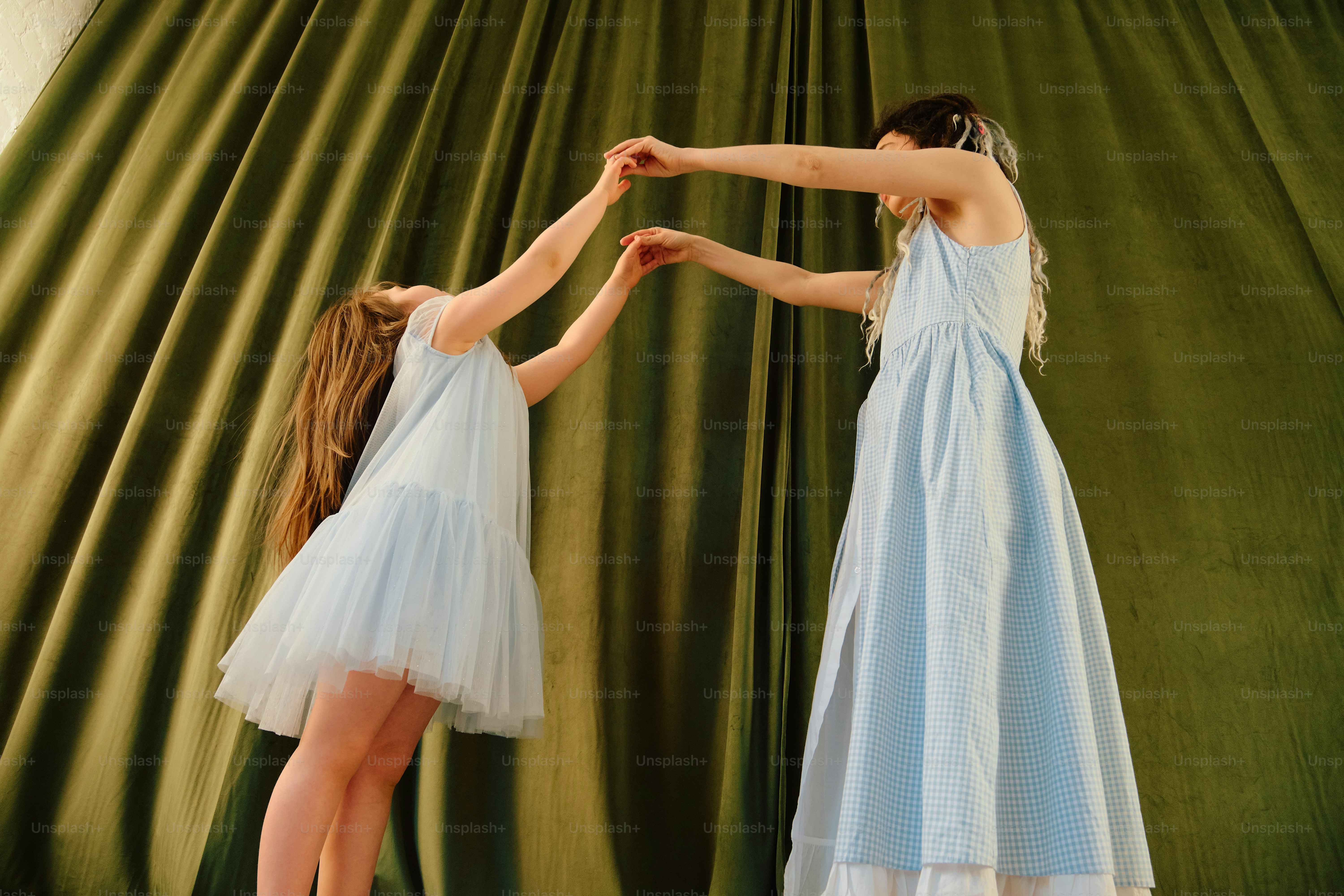 Two girls in light blue dresses holding hands