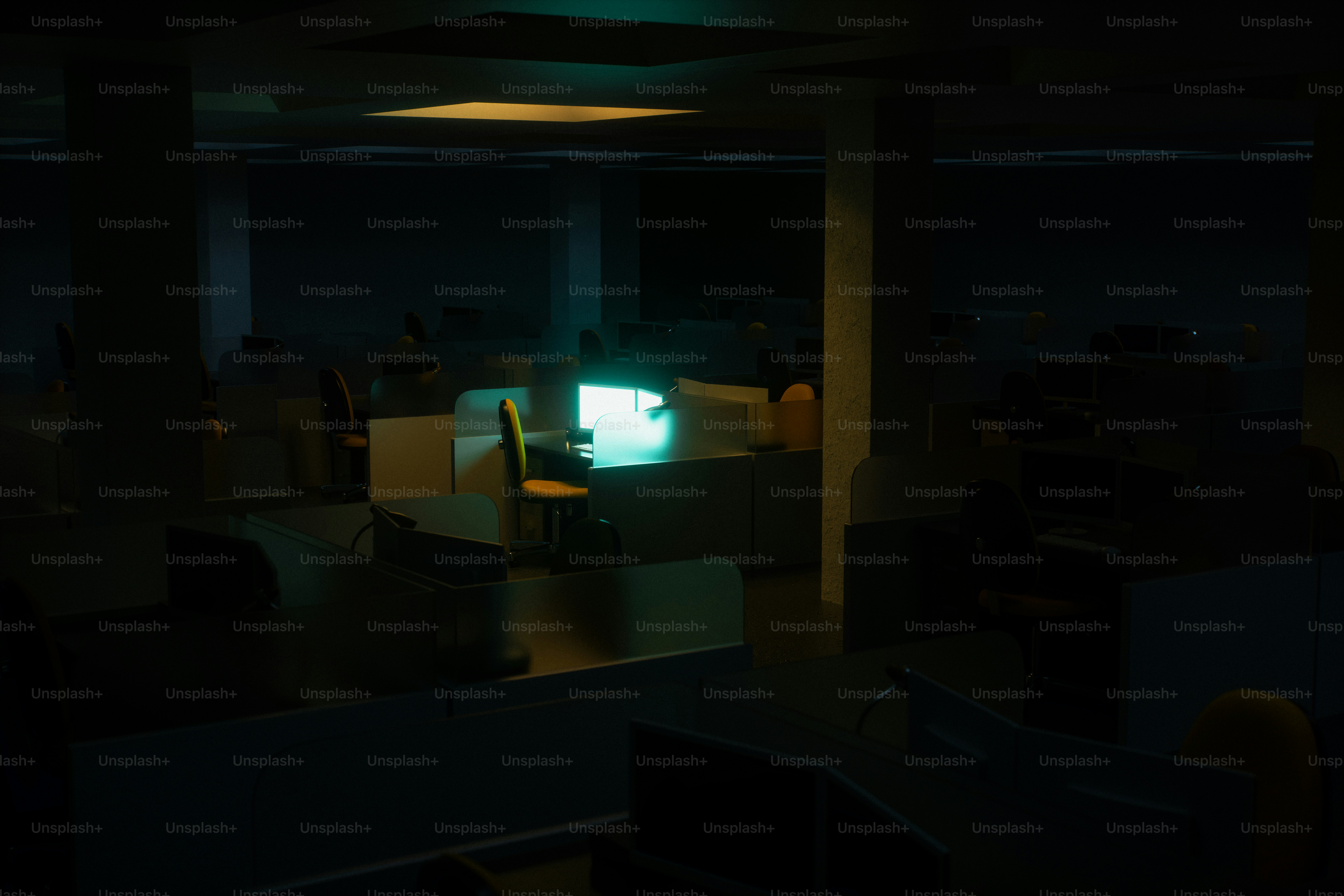 Bilik kantor yang remang-remang dengan monitor yang menyala.