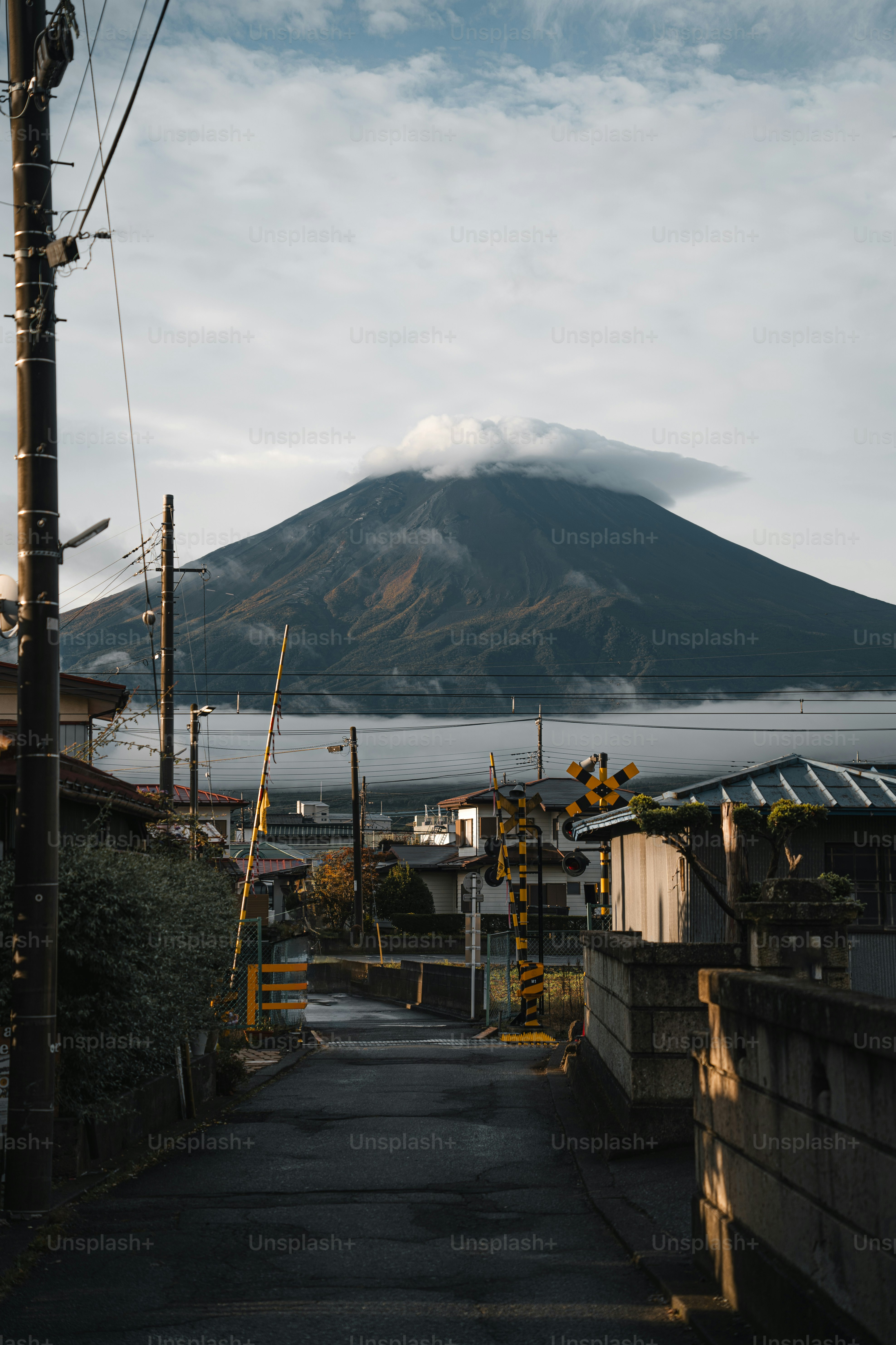 Mount fuji peeks through clouds above a quiet street.