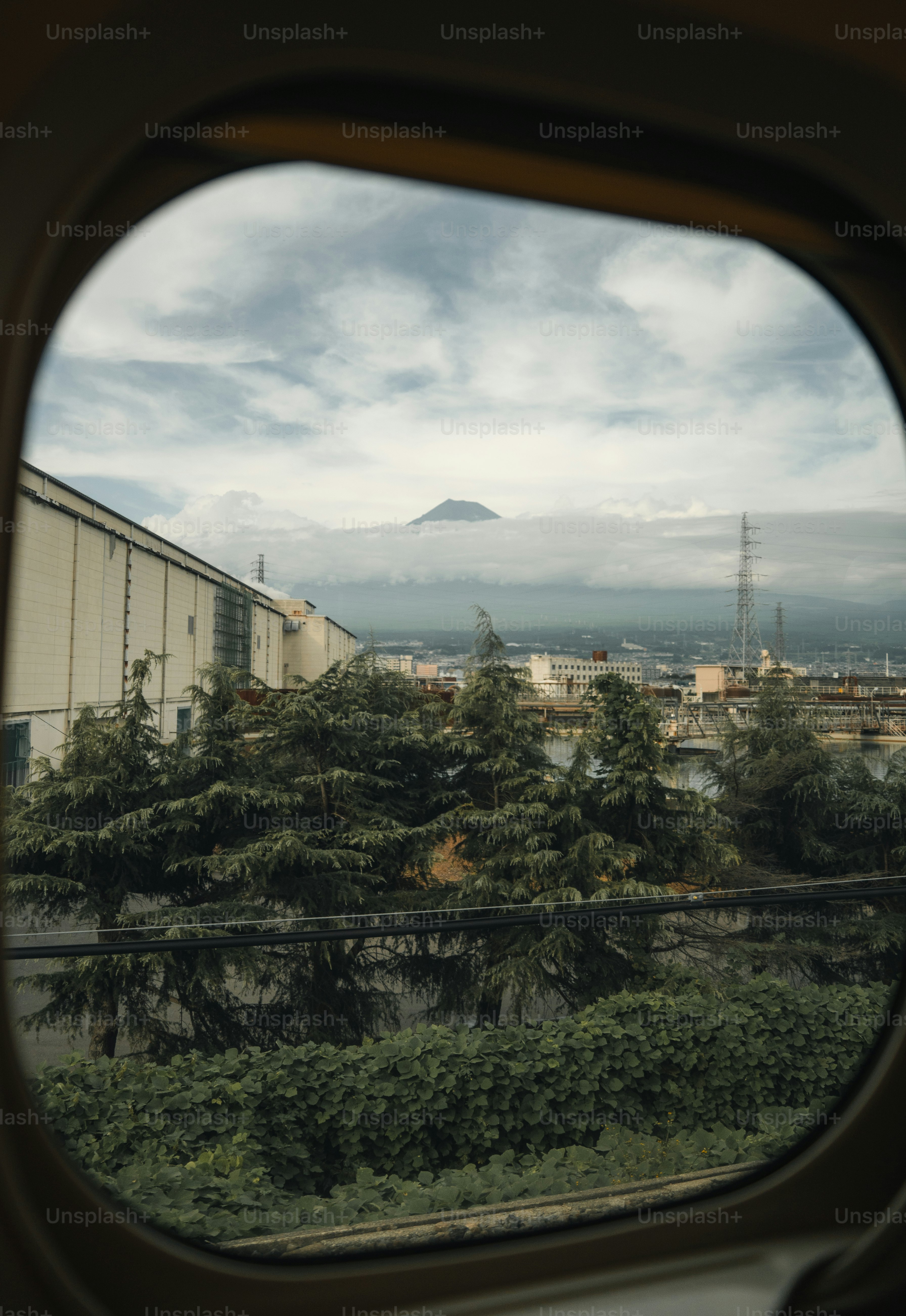 Mountain peak emerges from clouds over industrial buildings.