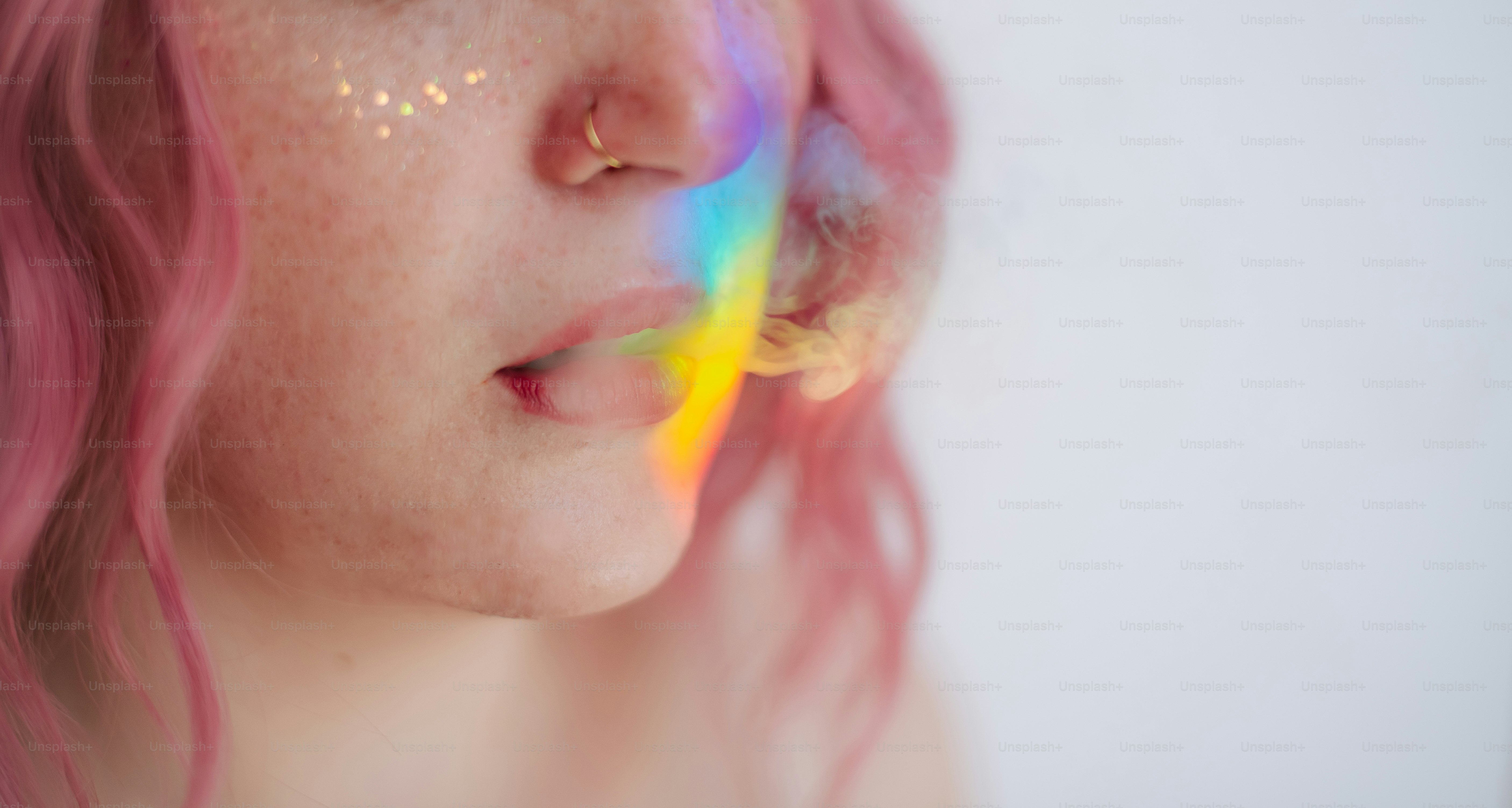 Wanita dengan rambut merah muda dan cahaya pelangi di wajah
