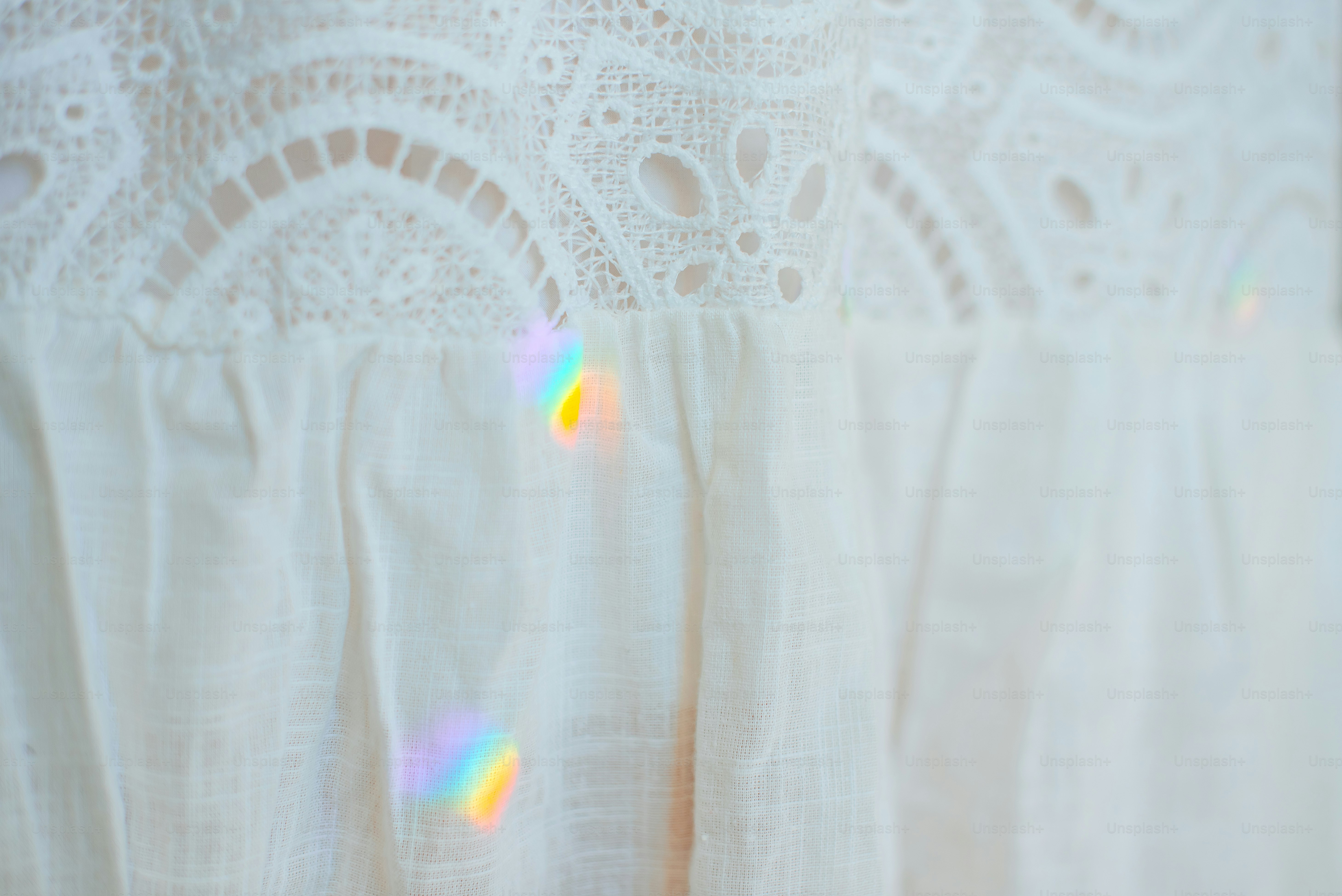 Close-up kain putih dengan pantulan cahaya pelangi.