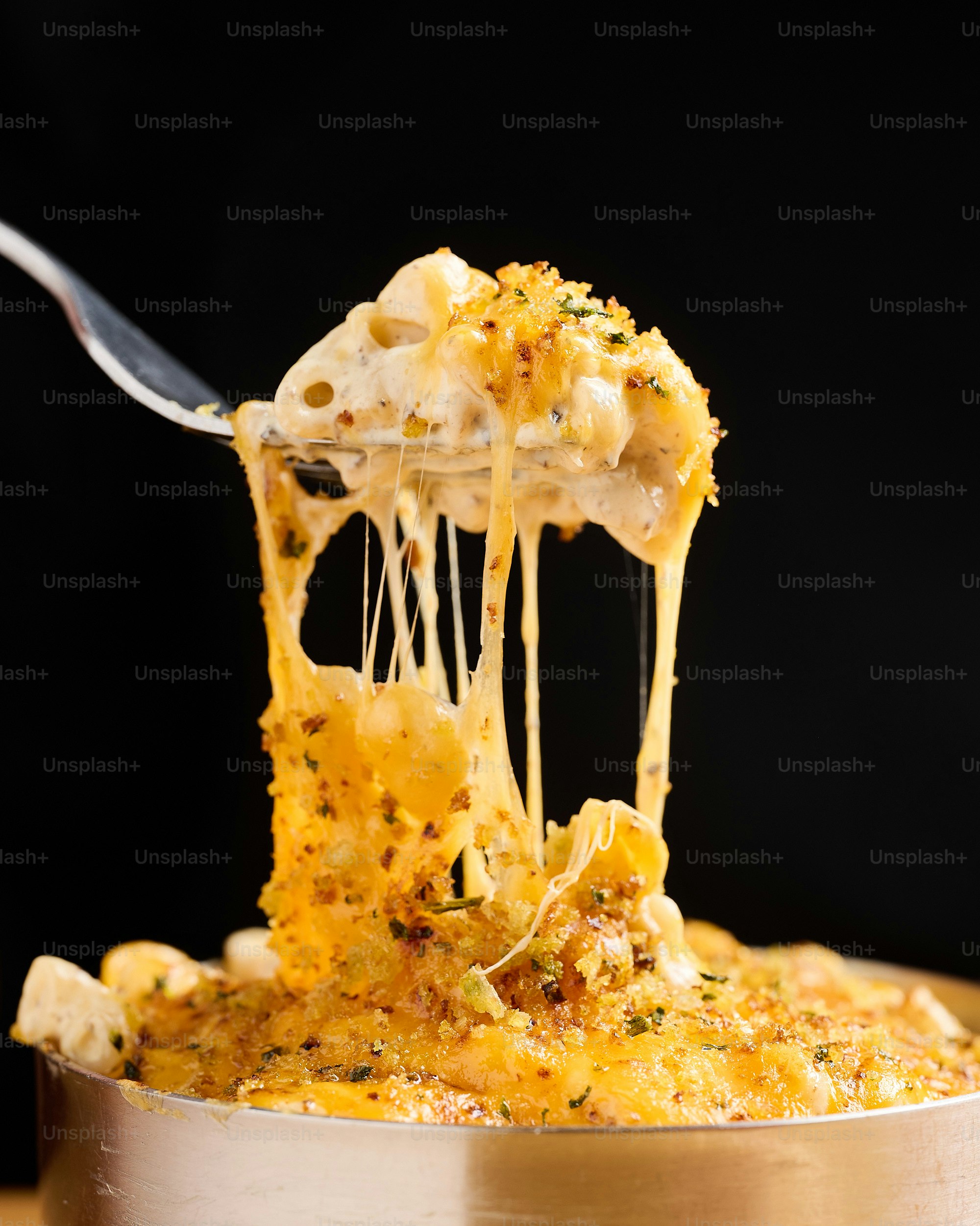 Um garfo tira macarrão com queijo e queijo de um prato.