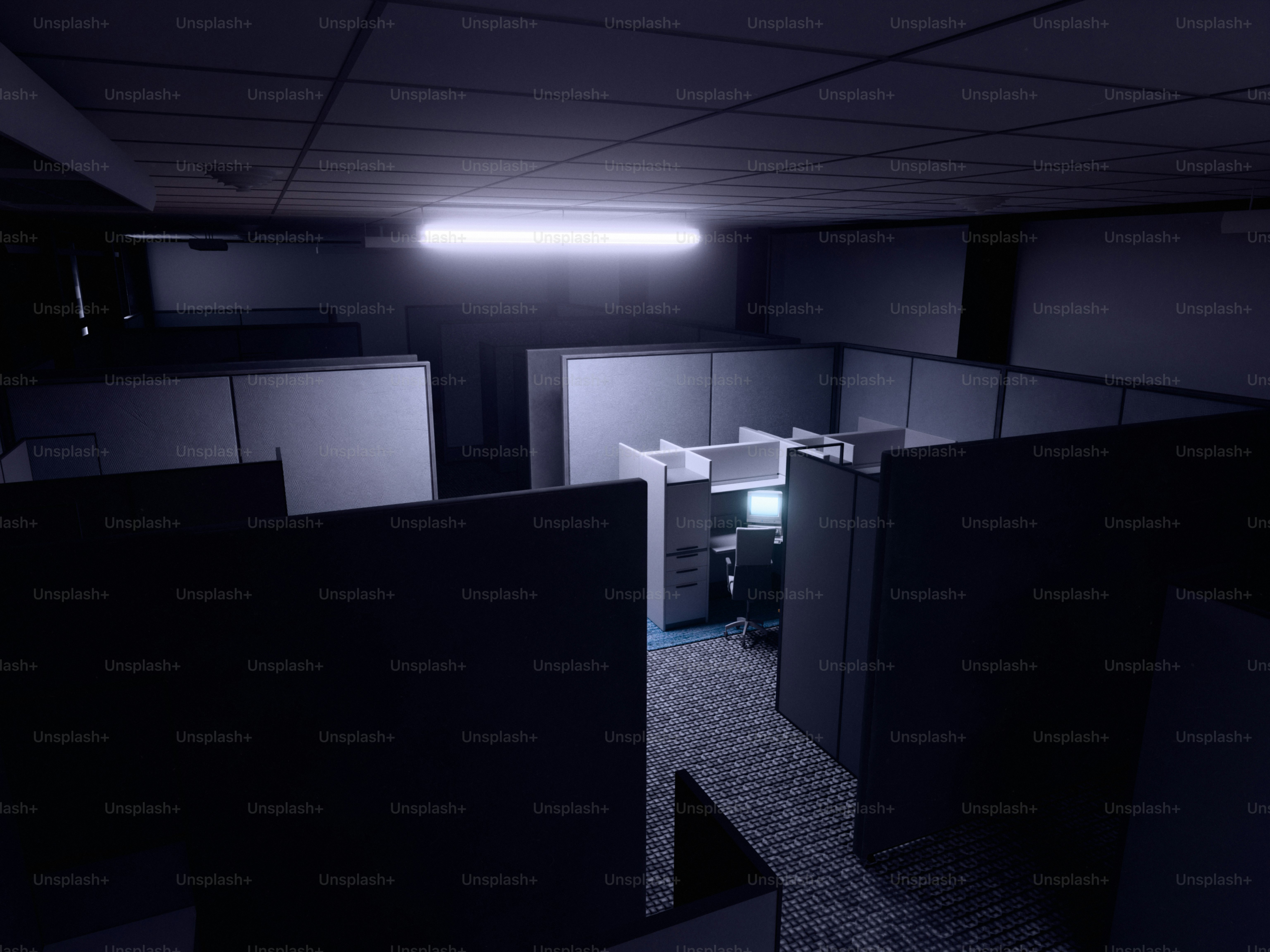 Bilik kantor gelap dengan satu komputer yang menyala