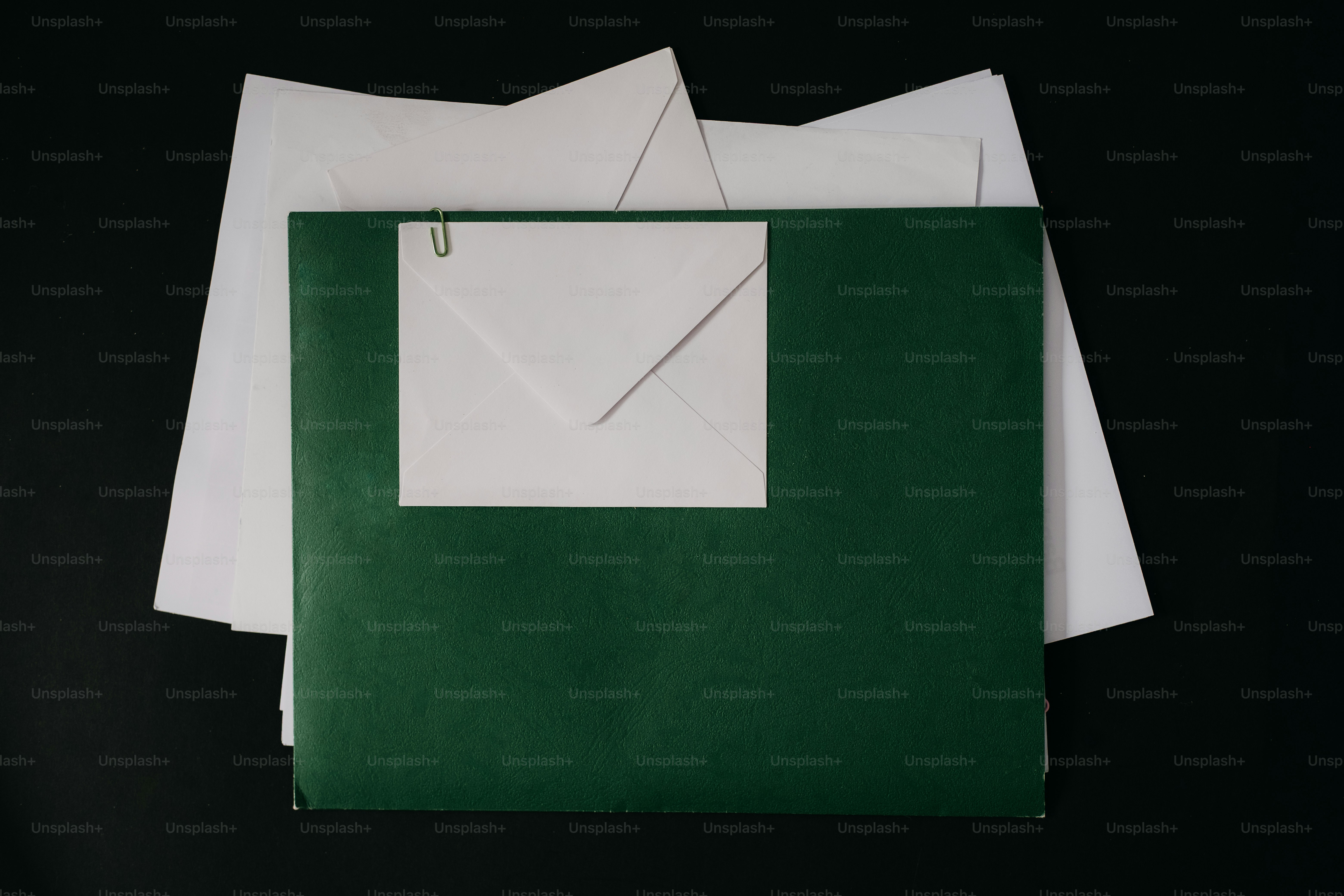 초록색 폴더에 흰 봉투와 종이클립이 들어 있어