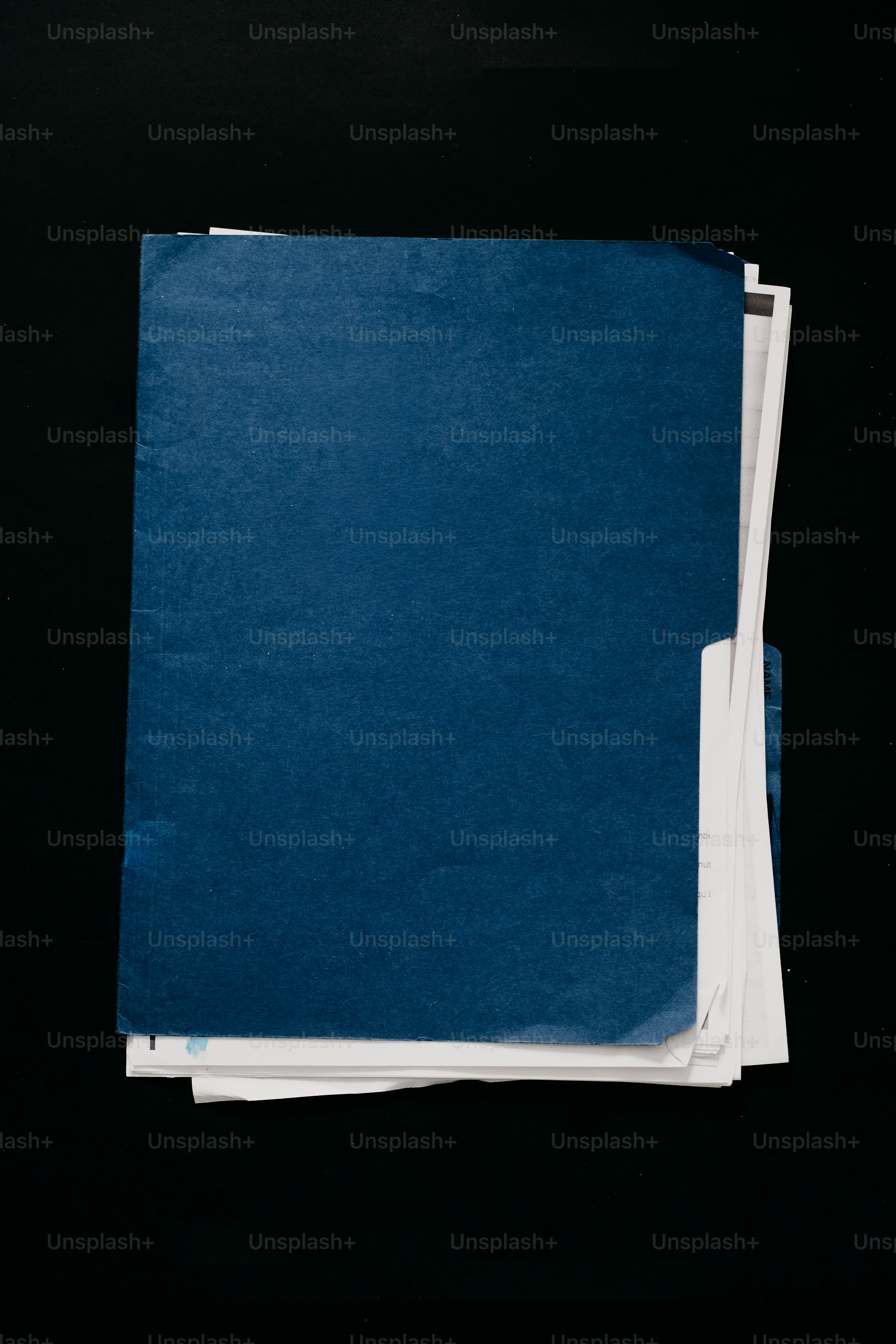 검은 배경에 쌓인 파란색 폴더와 종이 더미