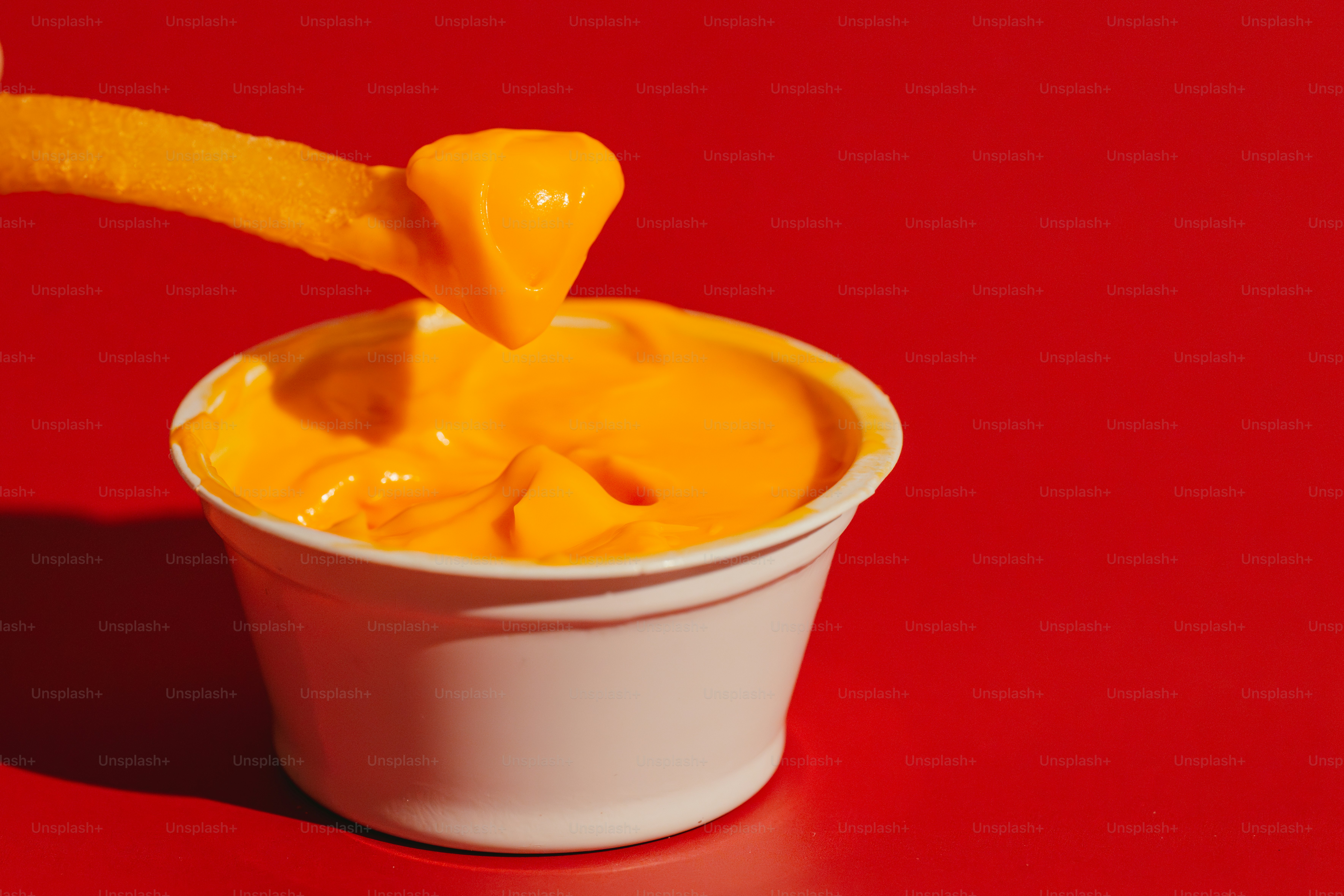 French fry dipping into a cup of cheese sauce