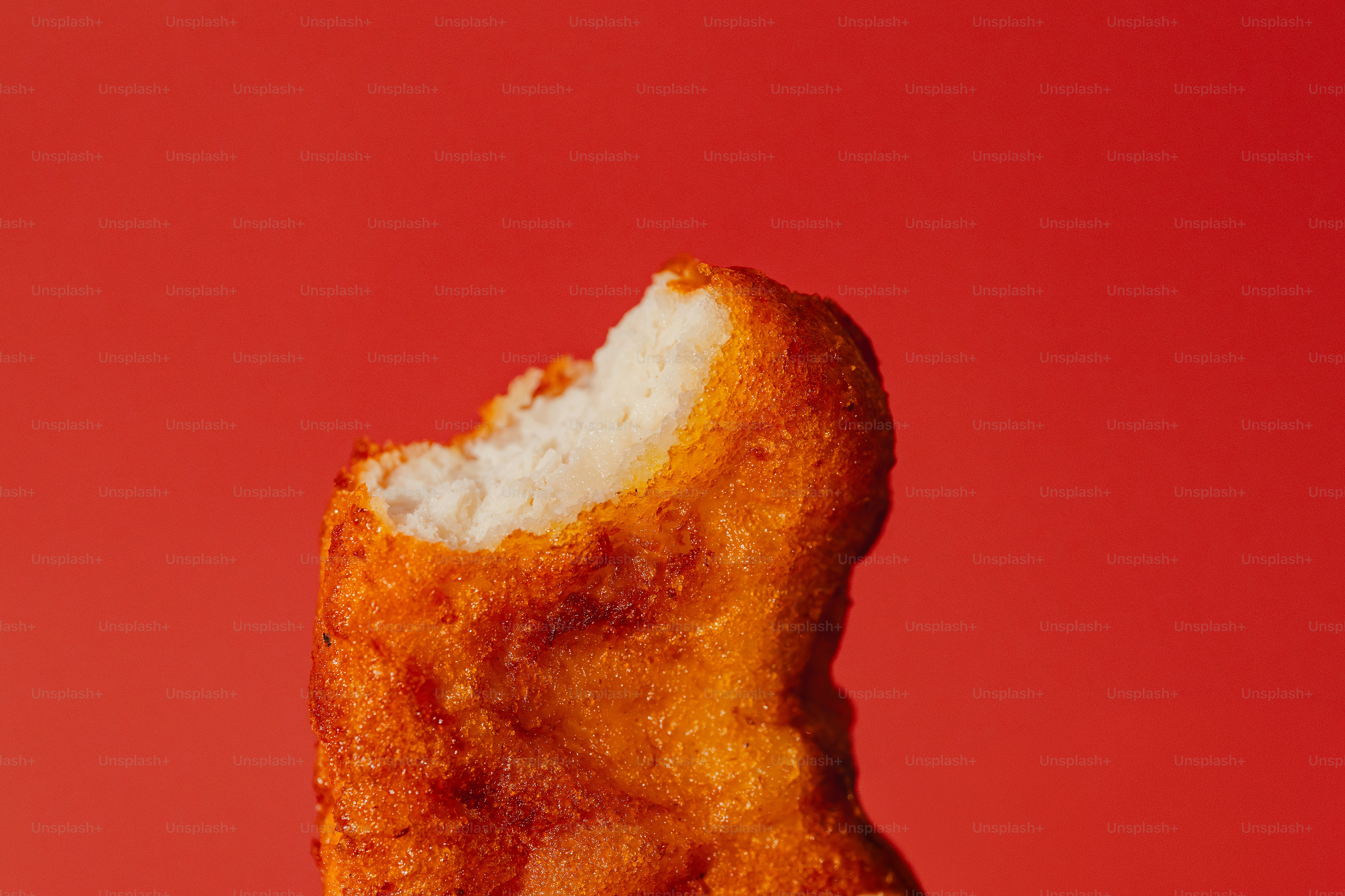 A bite taken out of a crispy fried chicken tender.