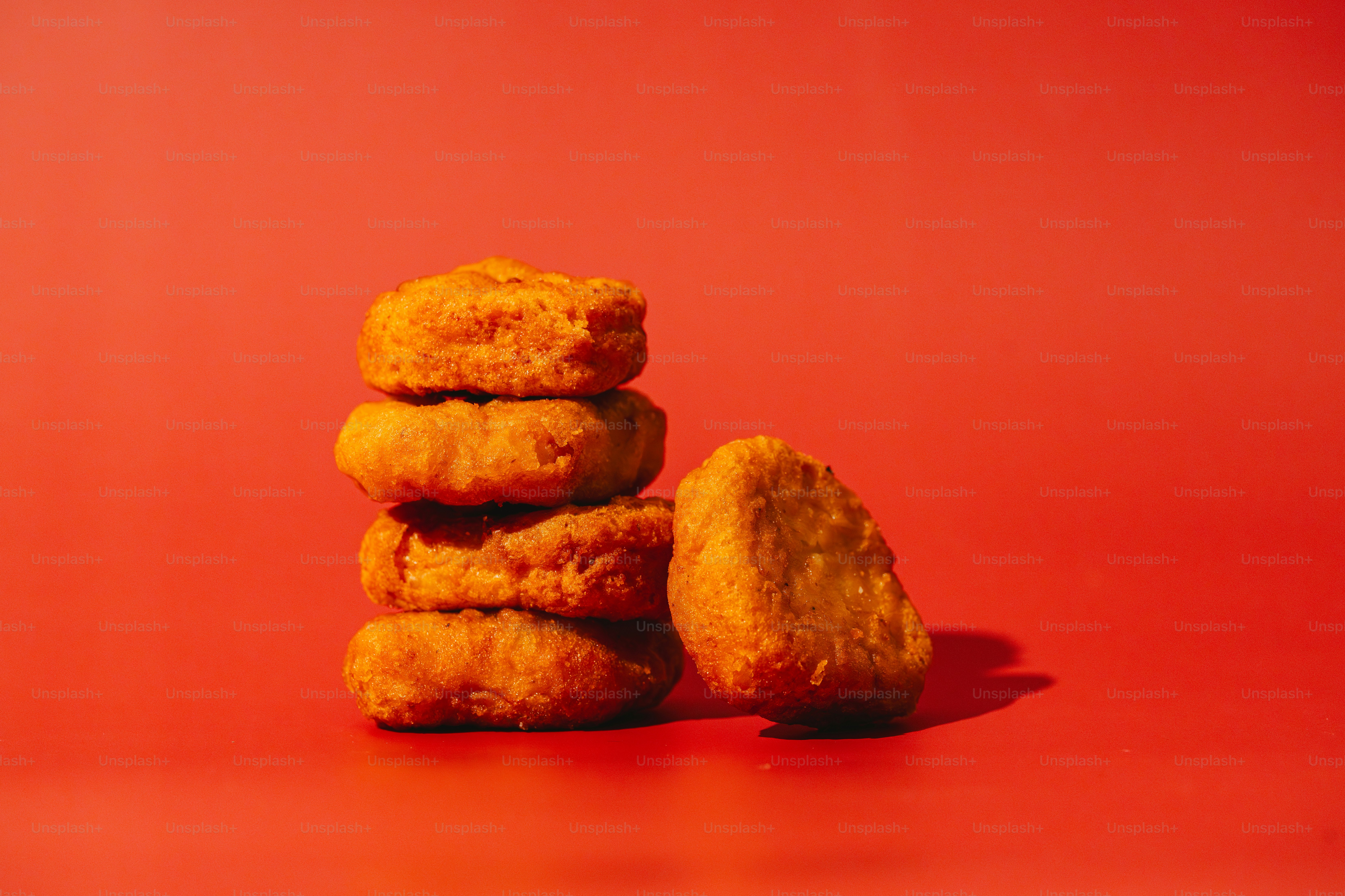 Stack of golden chicken nuggets on red background