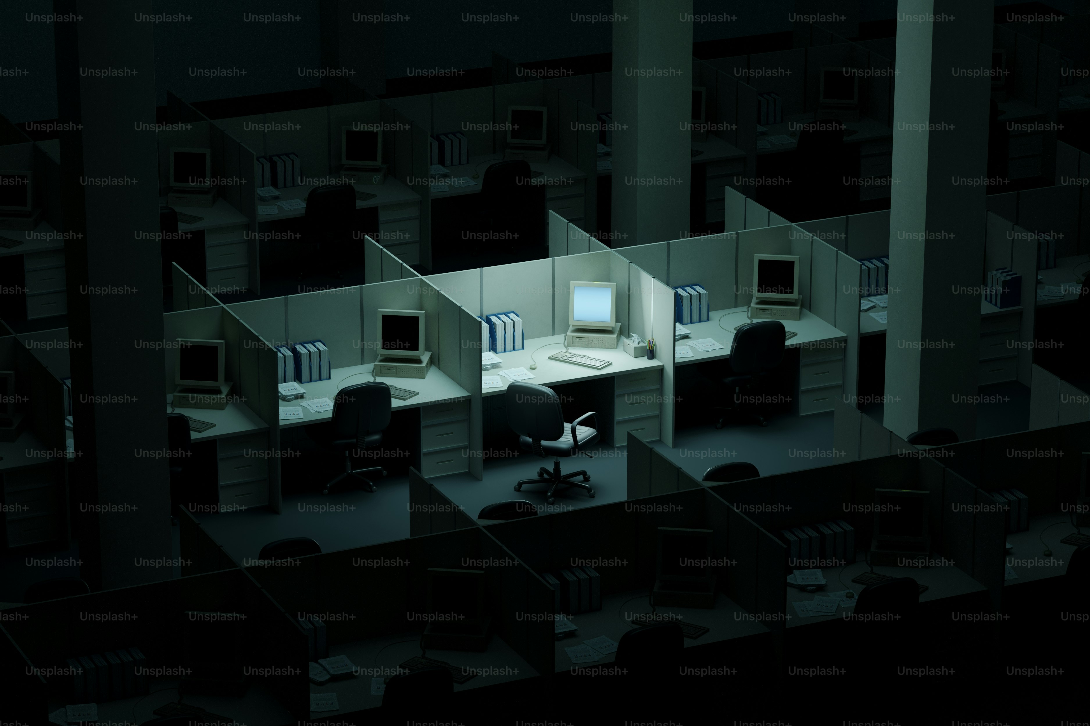 Empty office cubicles with one illuminated computer station at night ...