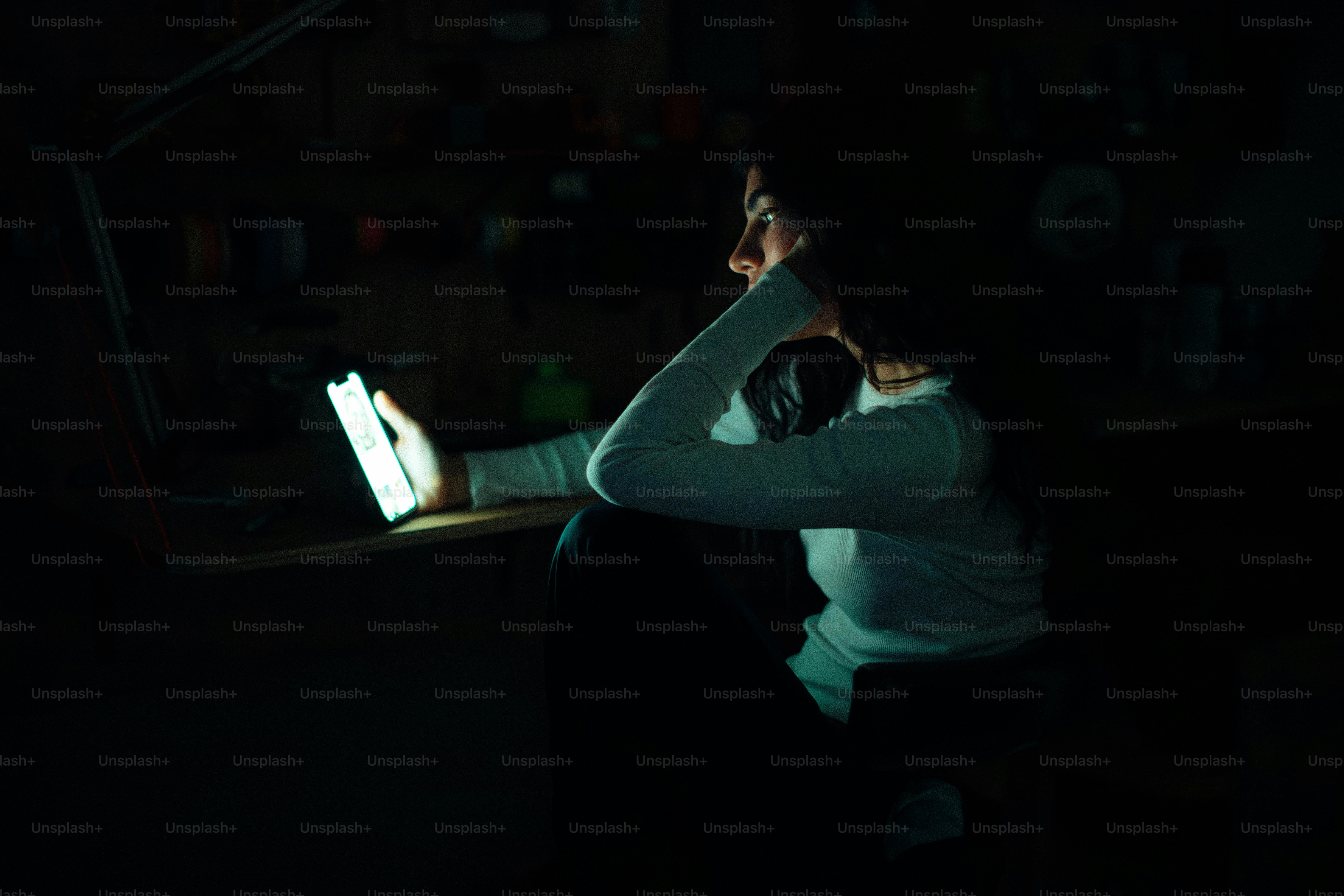 Woman illuminated by a tablet screen in darkness