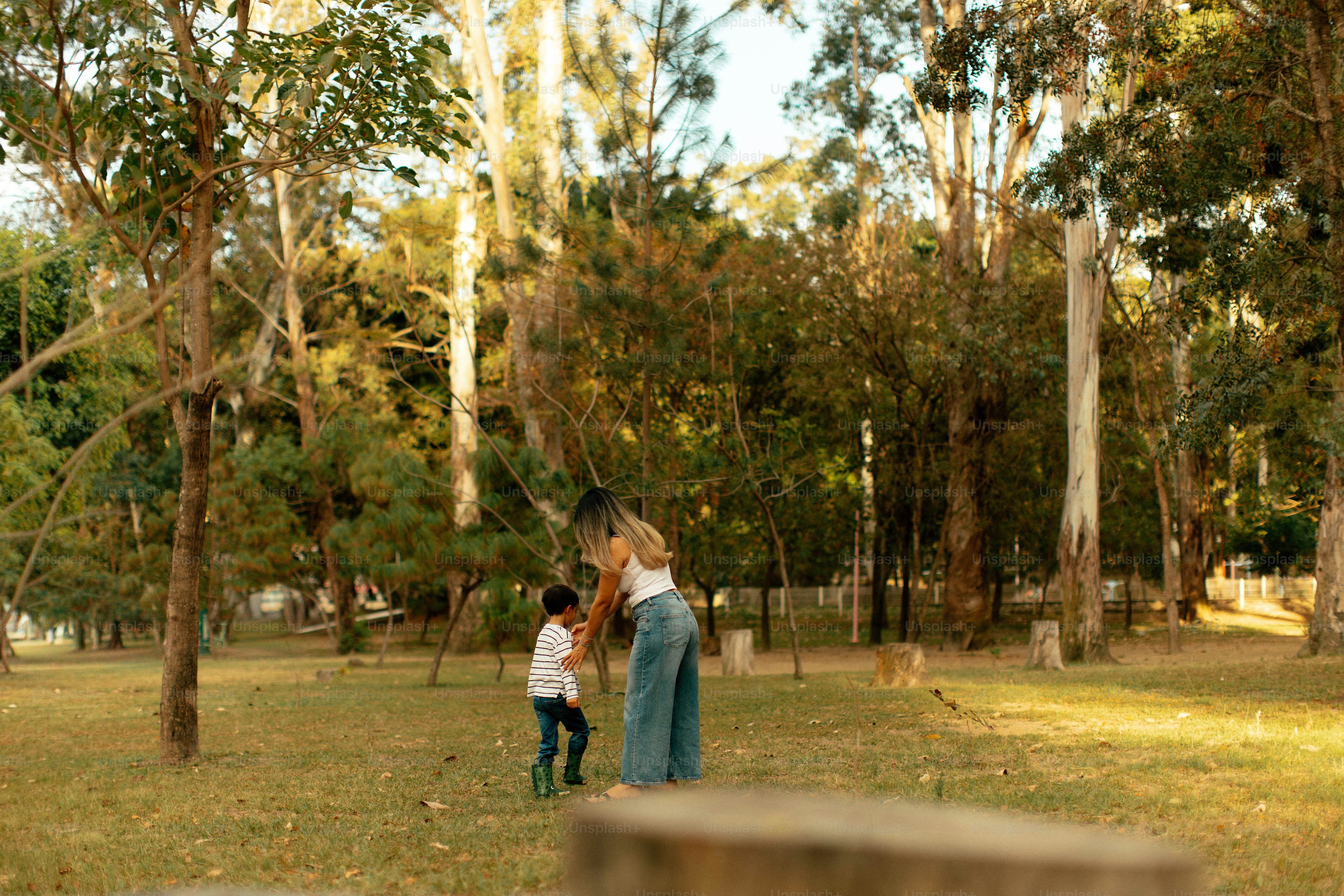 A woman and child playing in a grassy park.