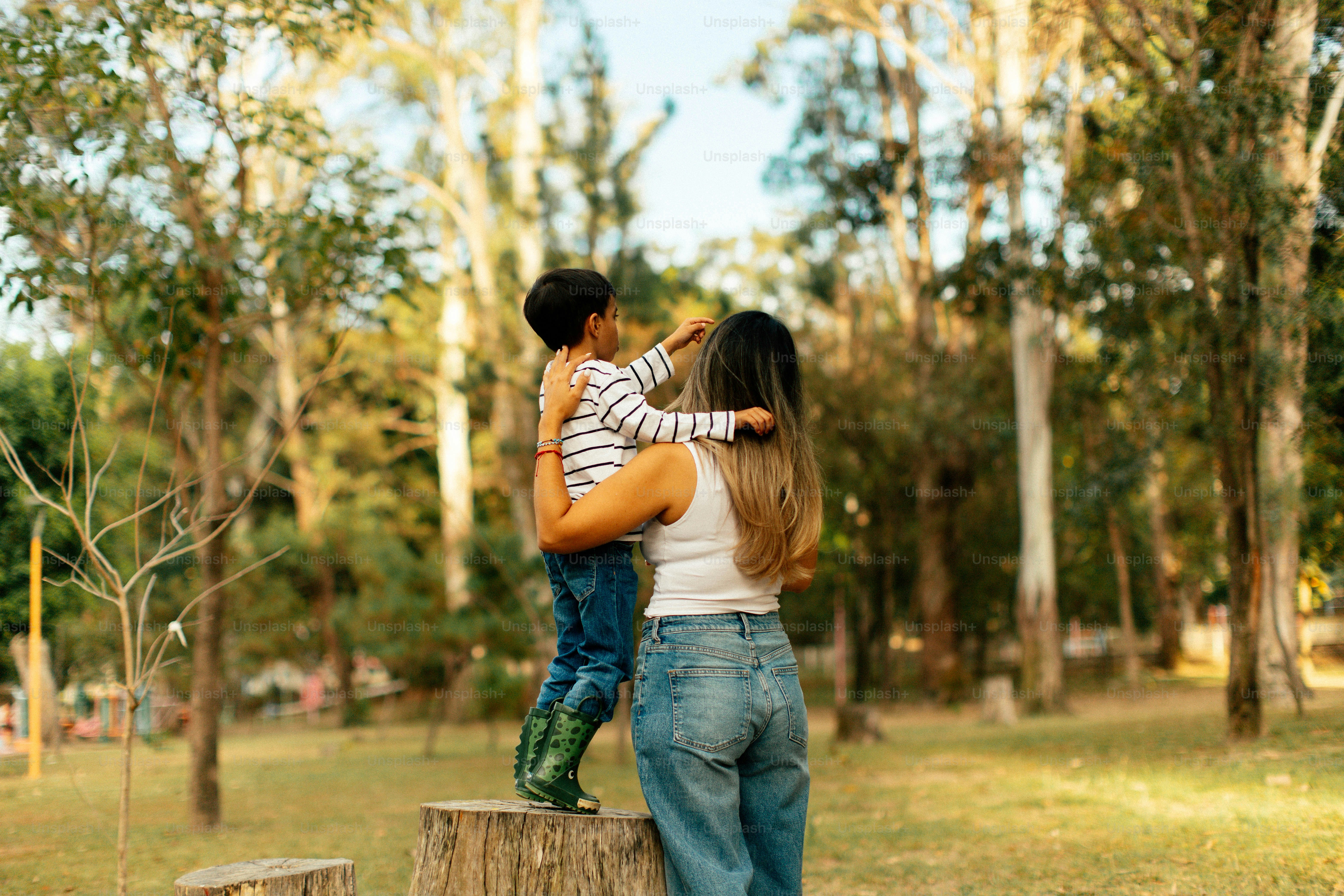 Mother holding son in a sunny park.