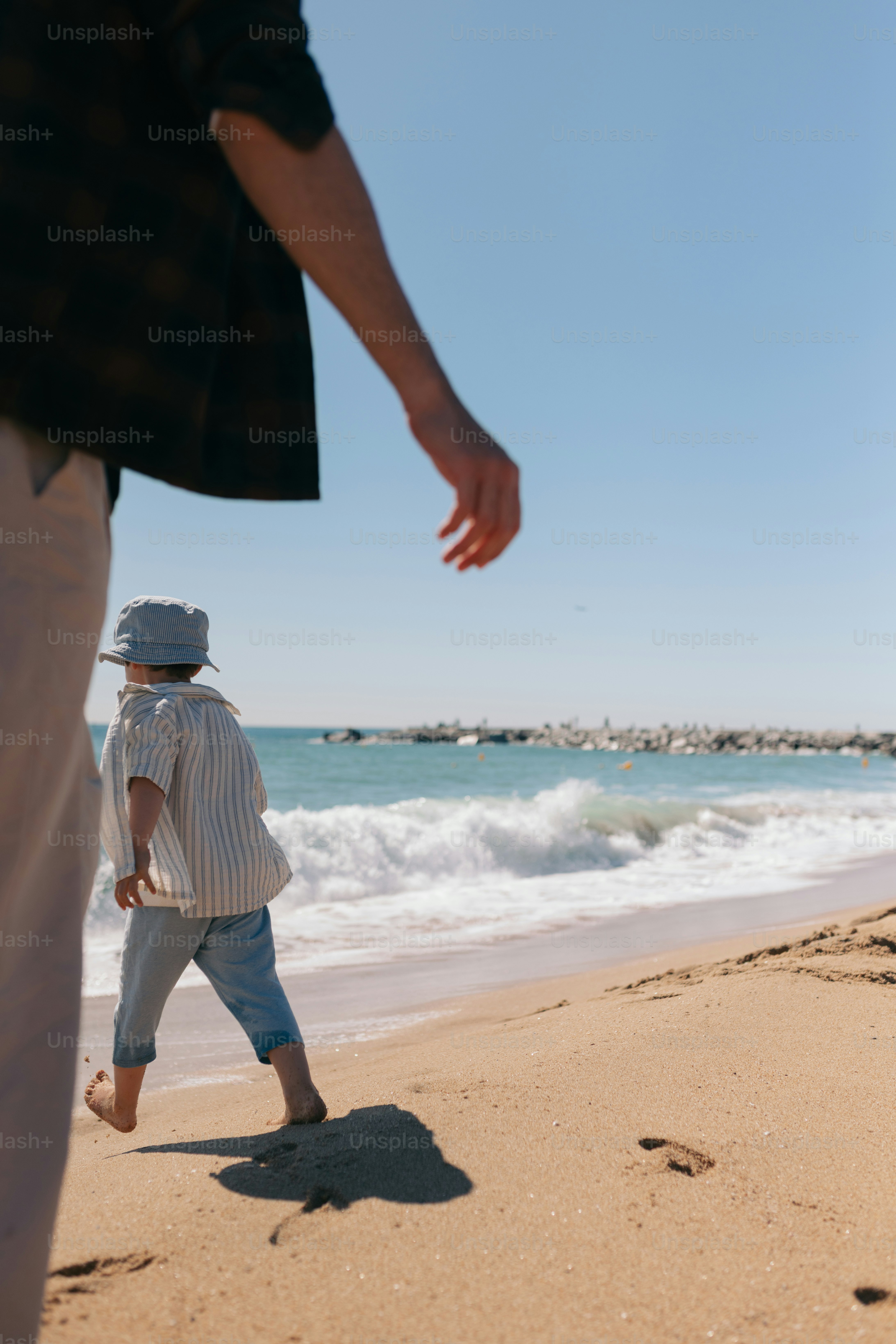 Seorang anak berjalan di pantai menuju laut.
