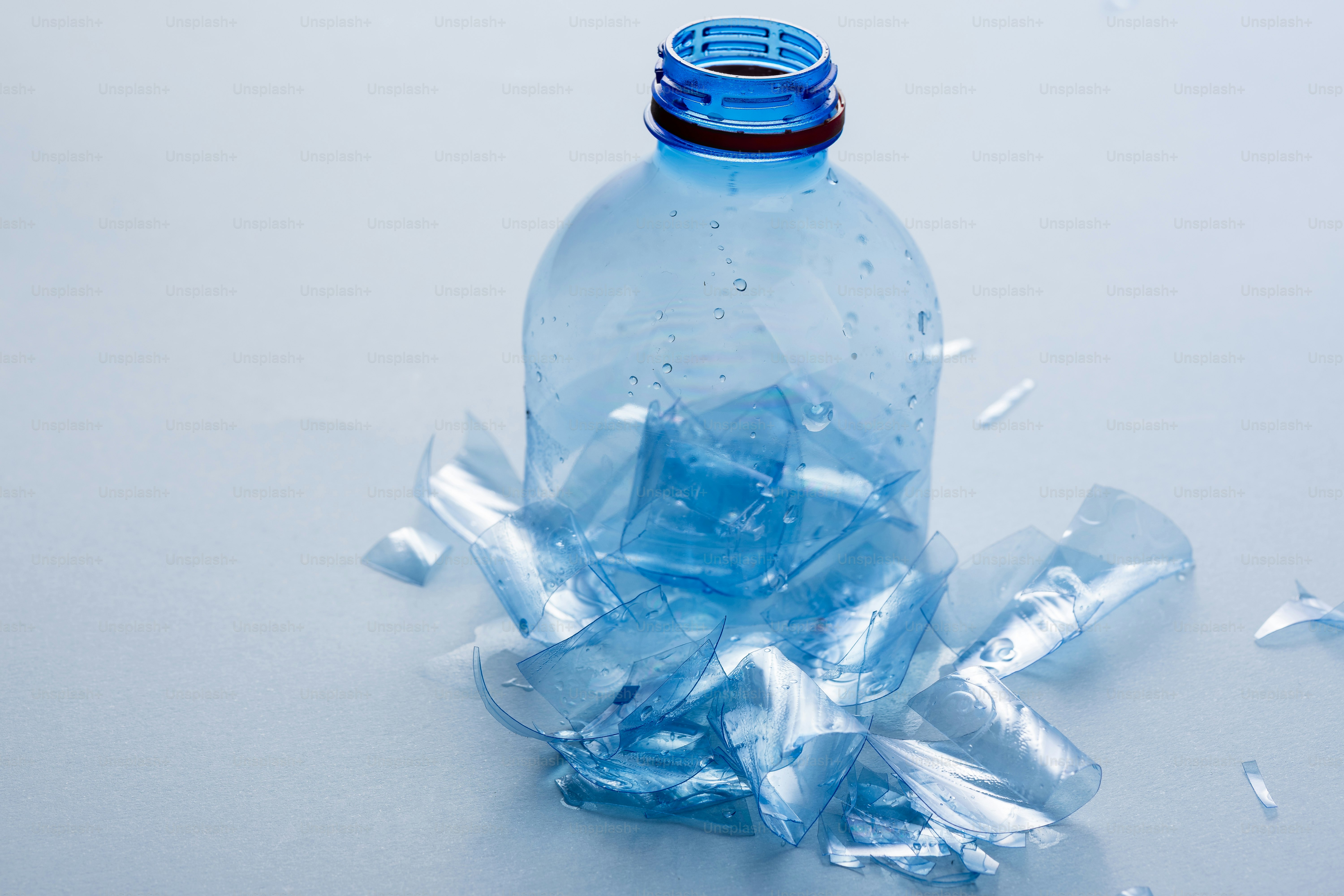 Una bottiglia di plastica blu schiacciata su una superficie chiara