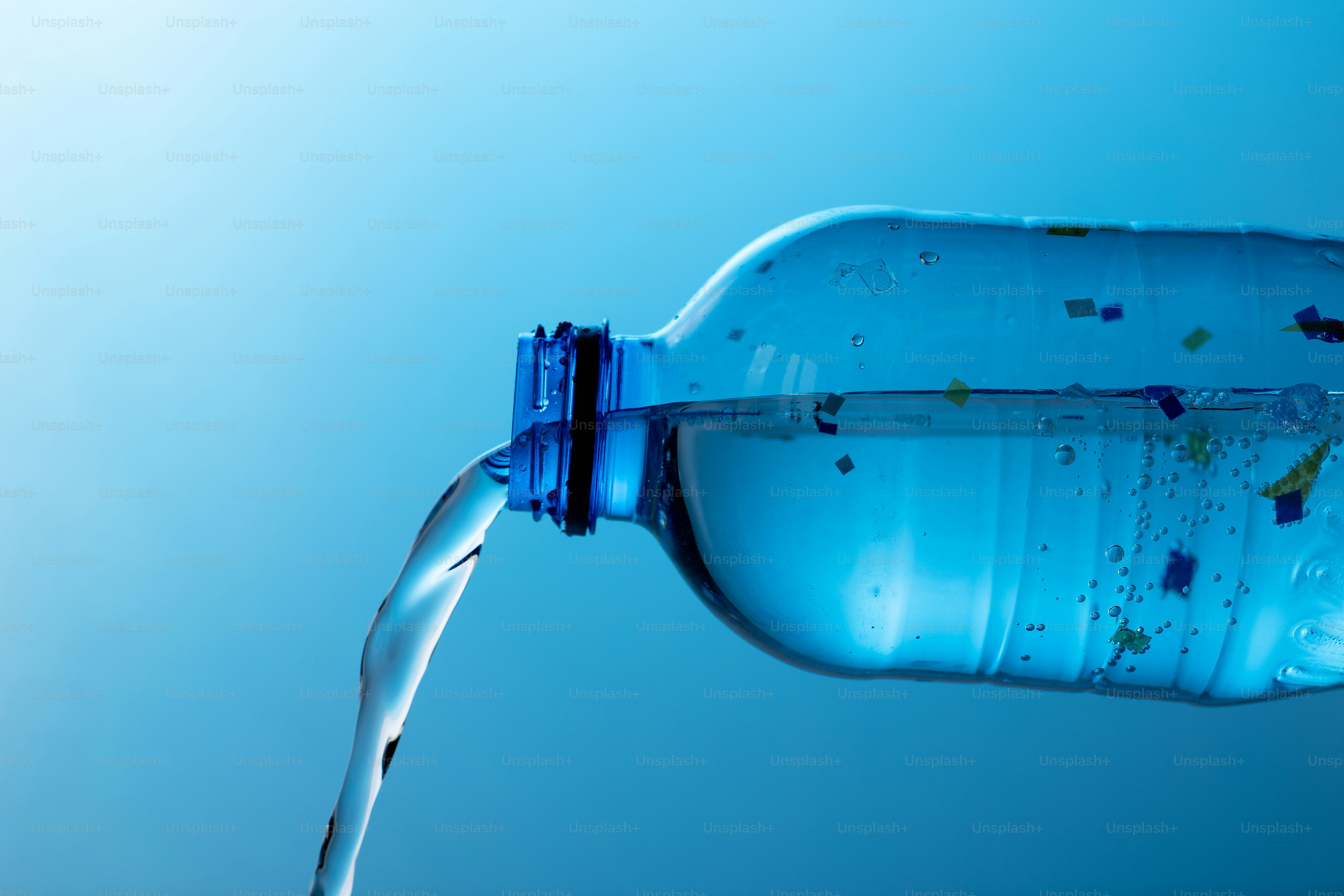 Clear liquid pouring from a blue plastic bottle