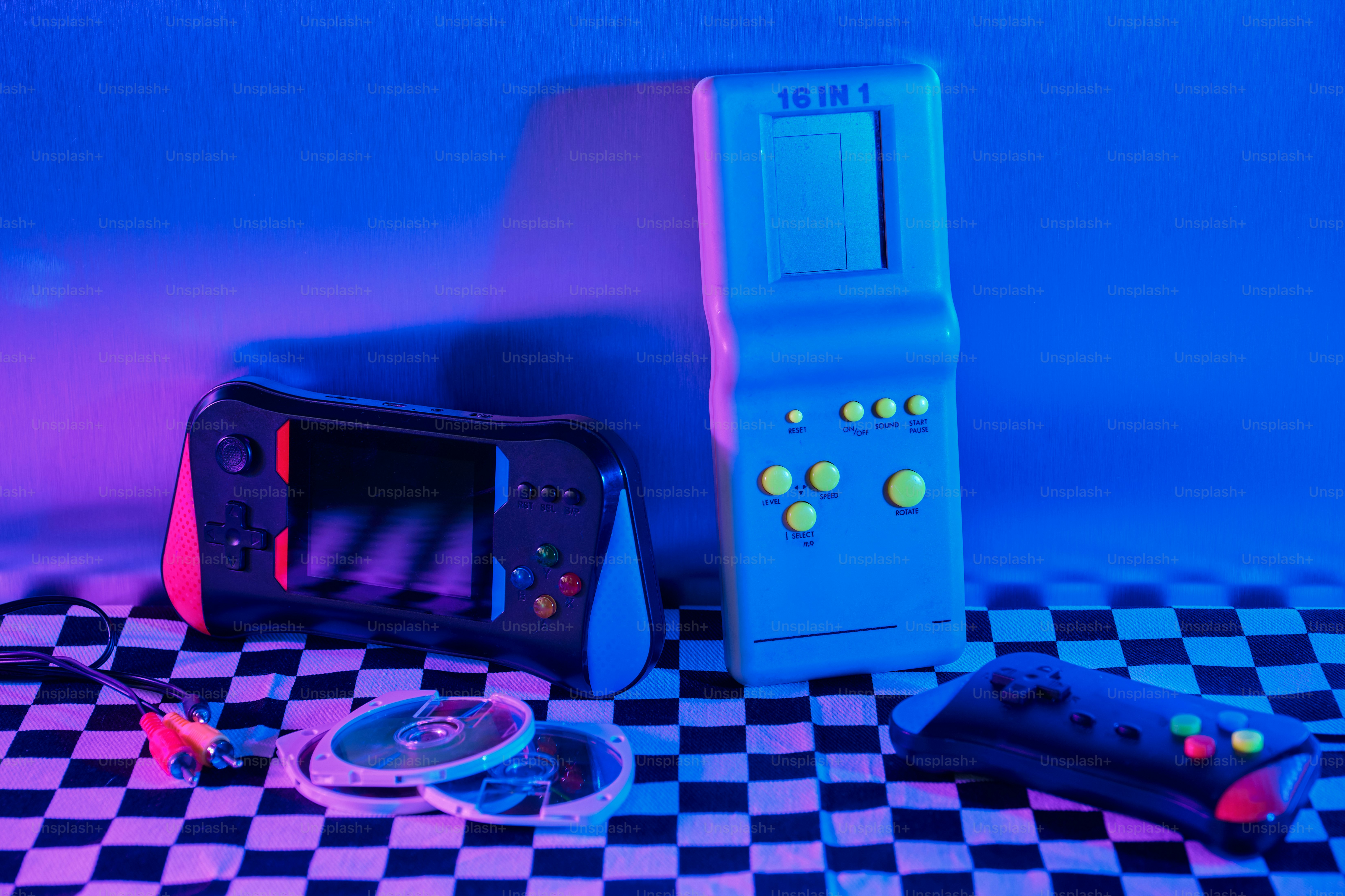 Zwei Retro-Spielkonsolen und Discs auf kariertem Stoff