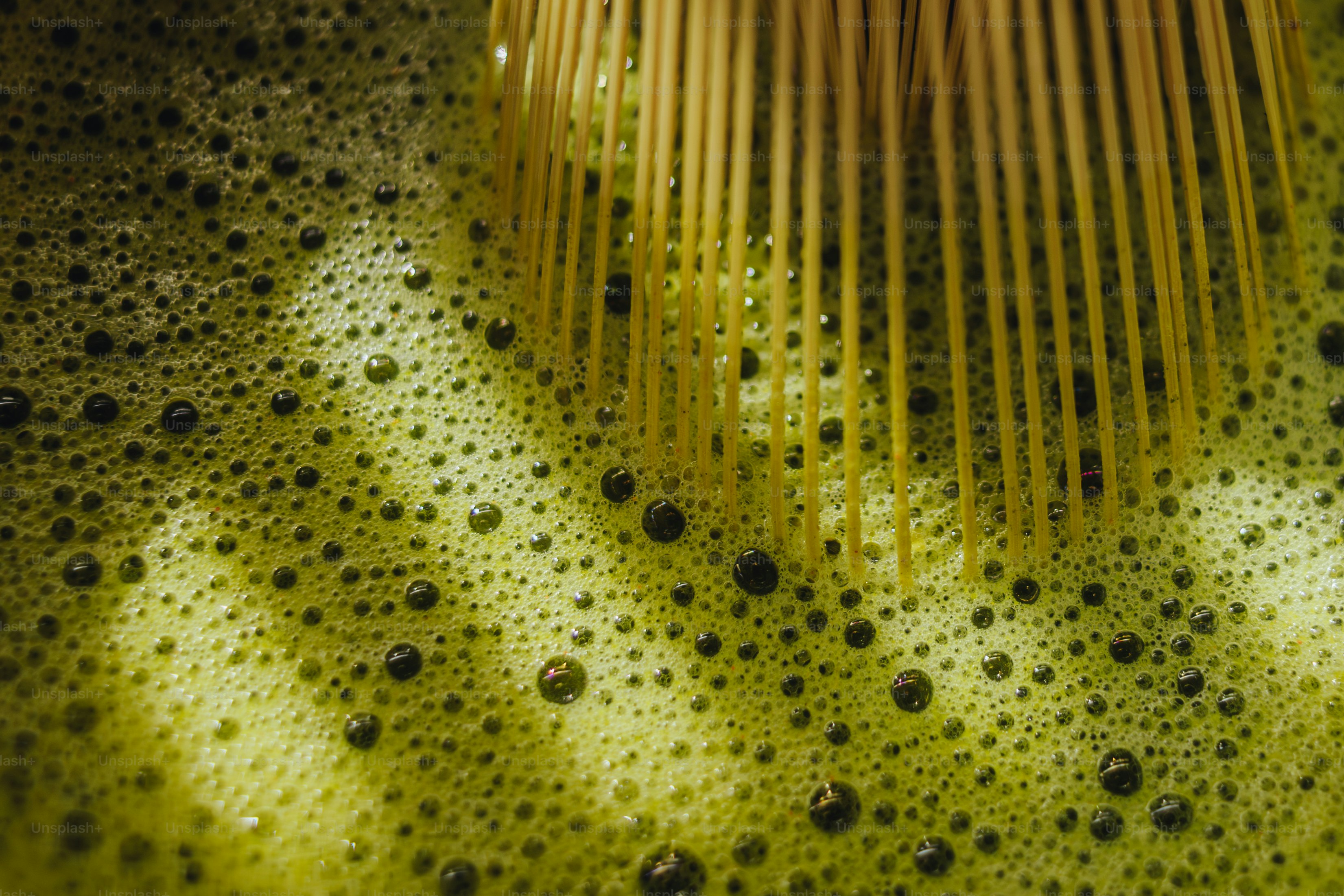 Batidor de bambú espumando té verde con burbujas