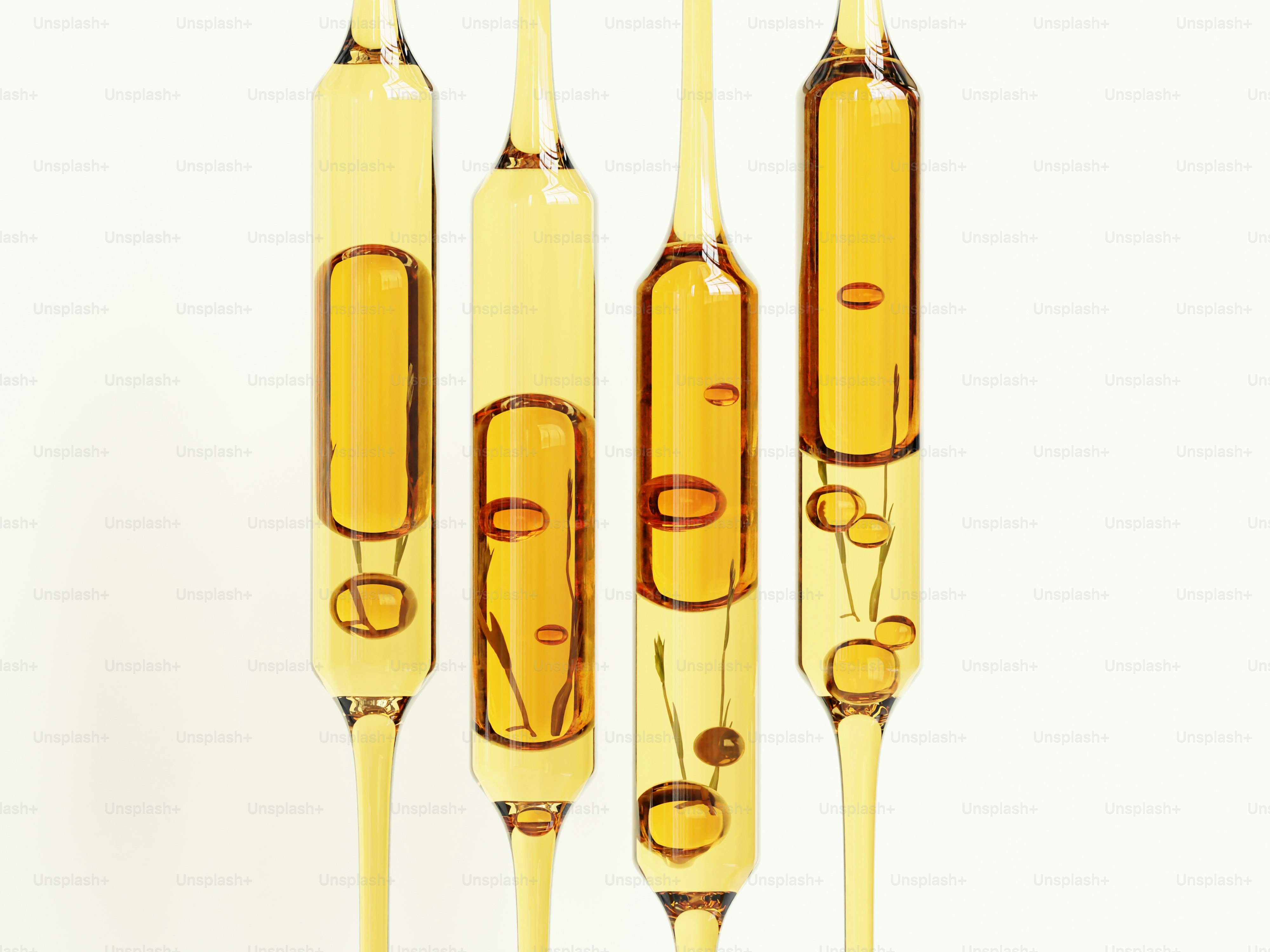 Cuatro ampollas de cristal llenas de líquido amarillo y burbujas