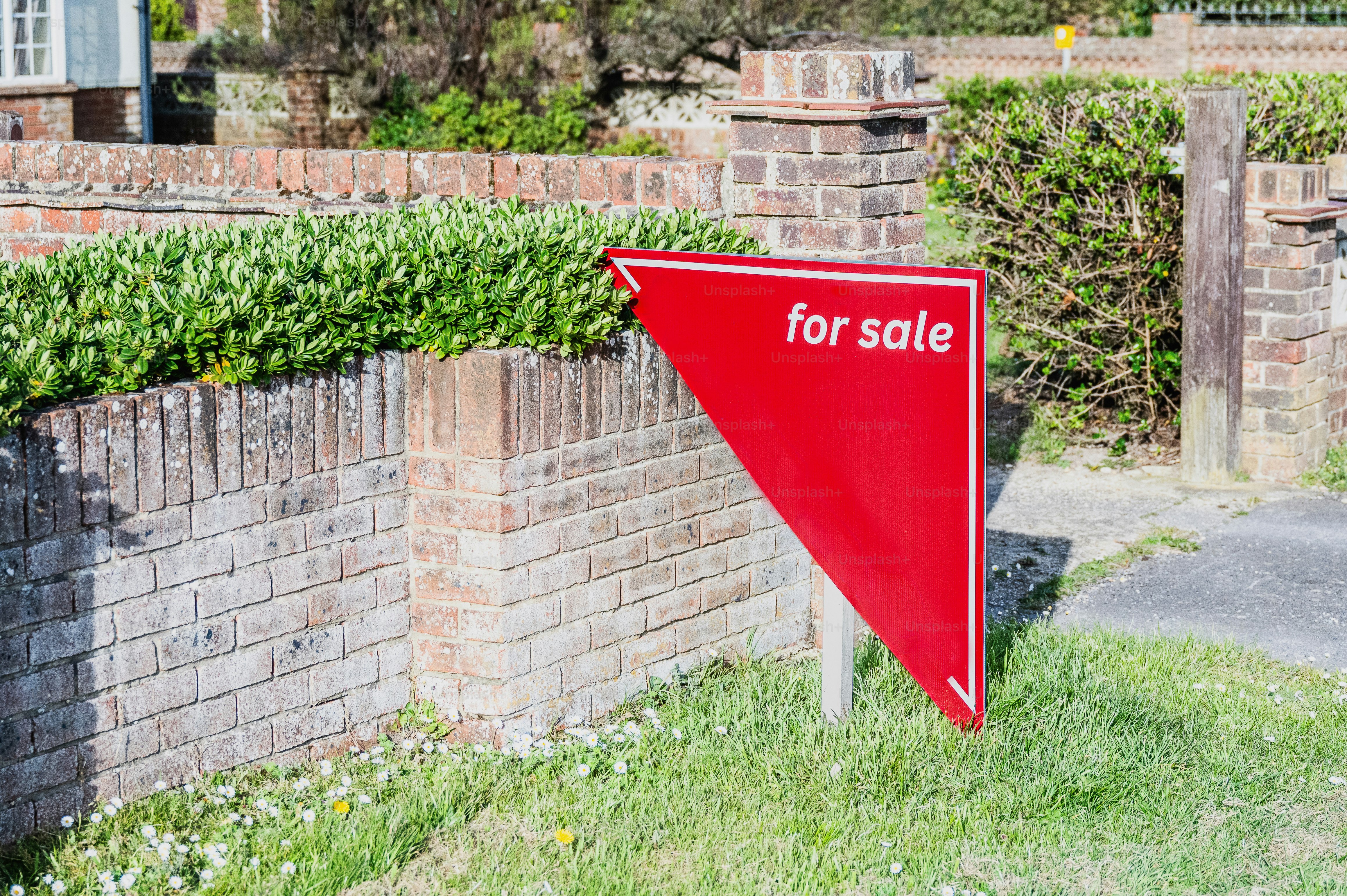 Panneau rouge à vendre devant un mur de briques