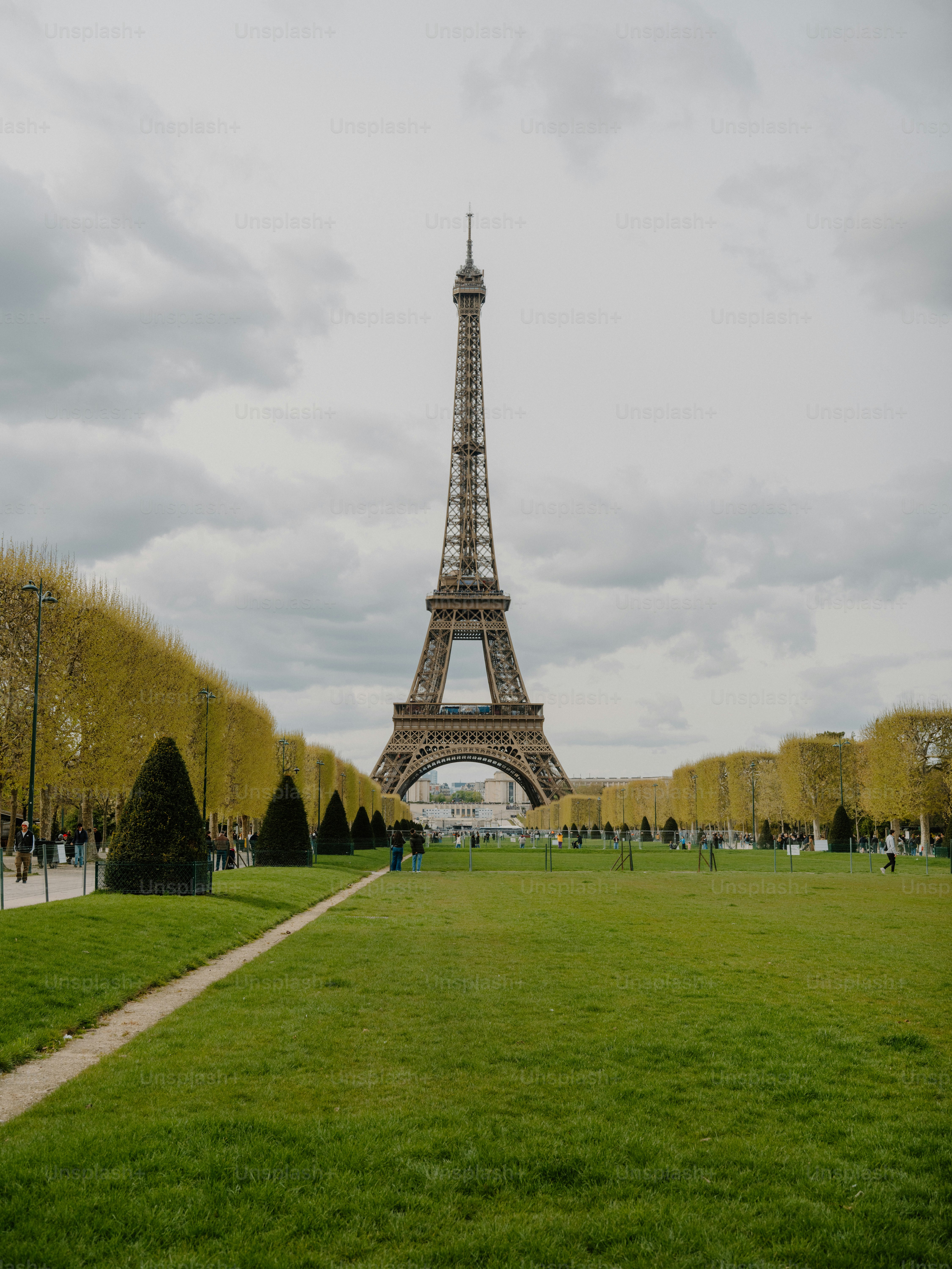 The eiffel tower stands tall in paris with green lawns.