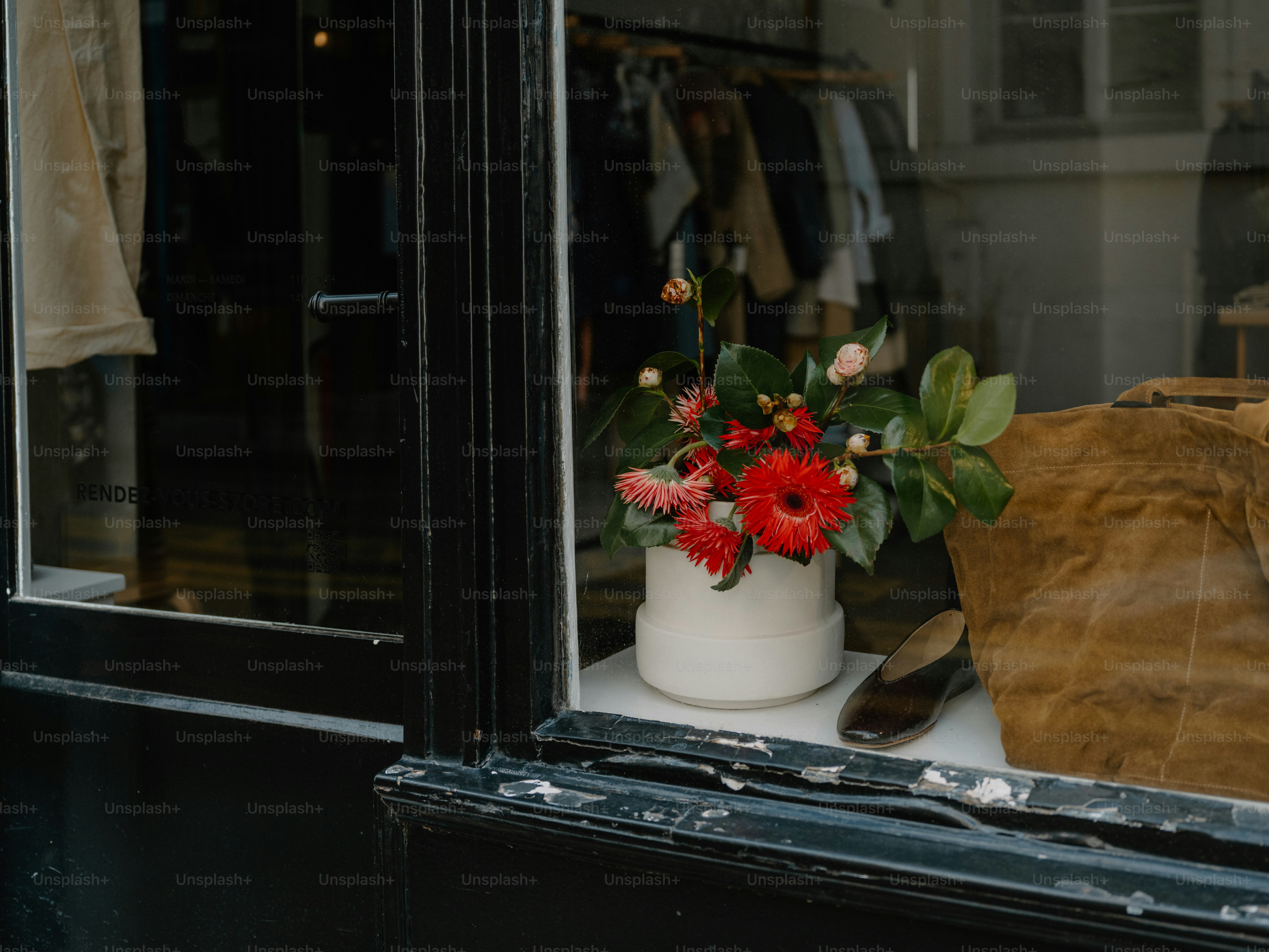 Um vaso de flores vermelhas está na vitrine de uma loja.