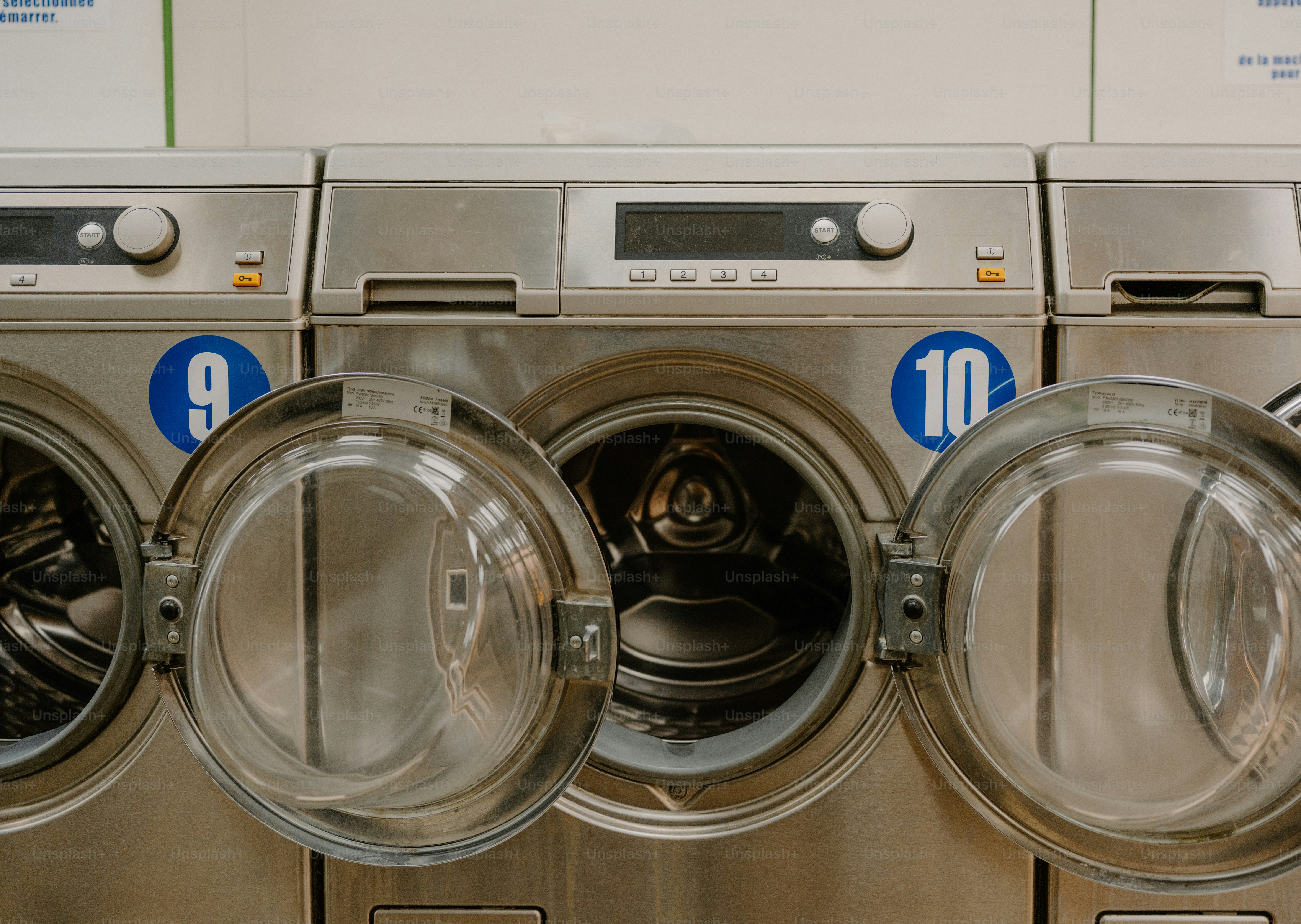 Row of washing machines with open doors
