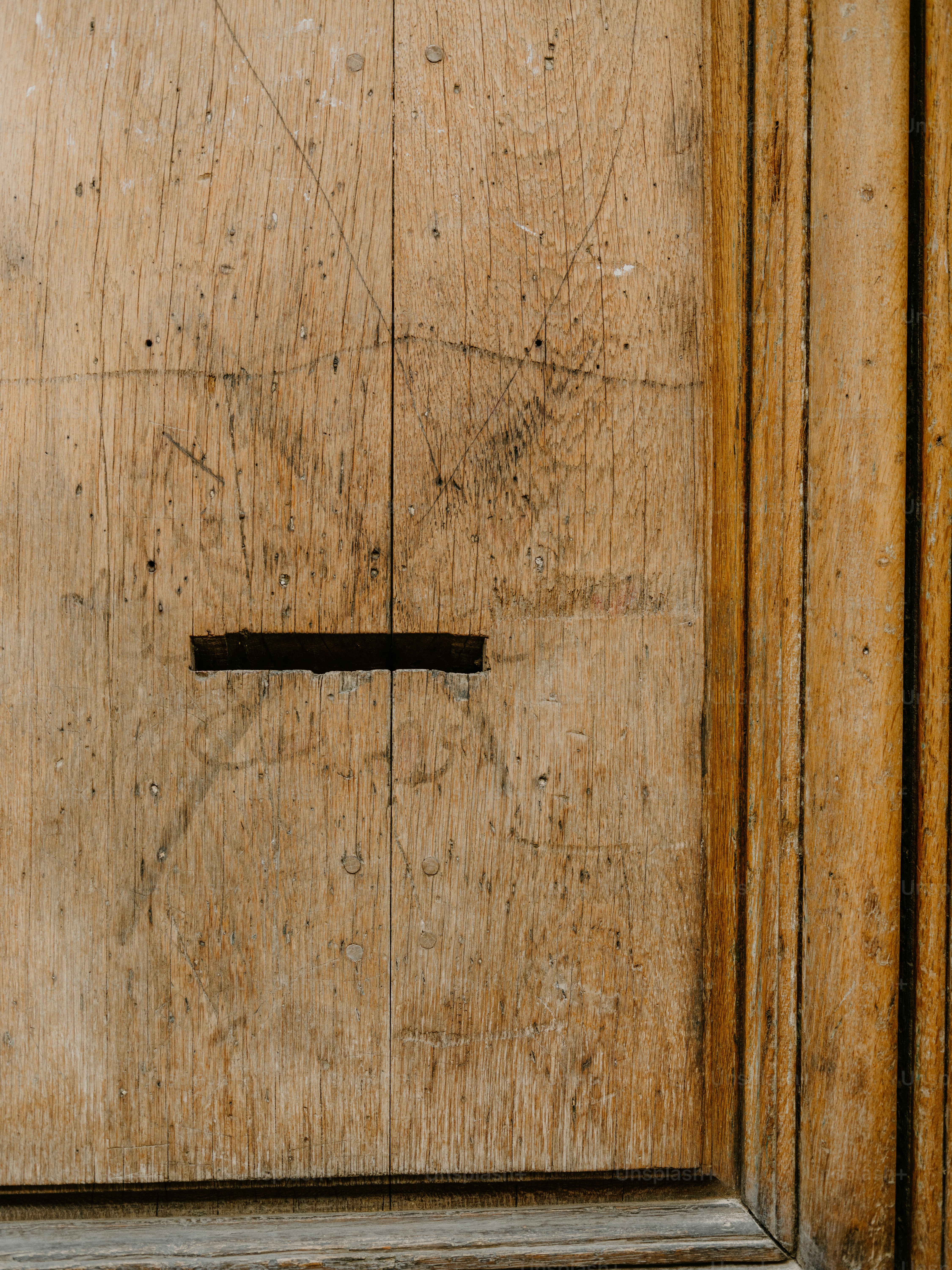 Old wooden door with a narrow mail slot.