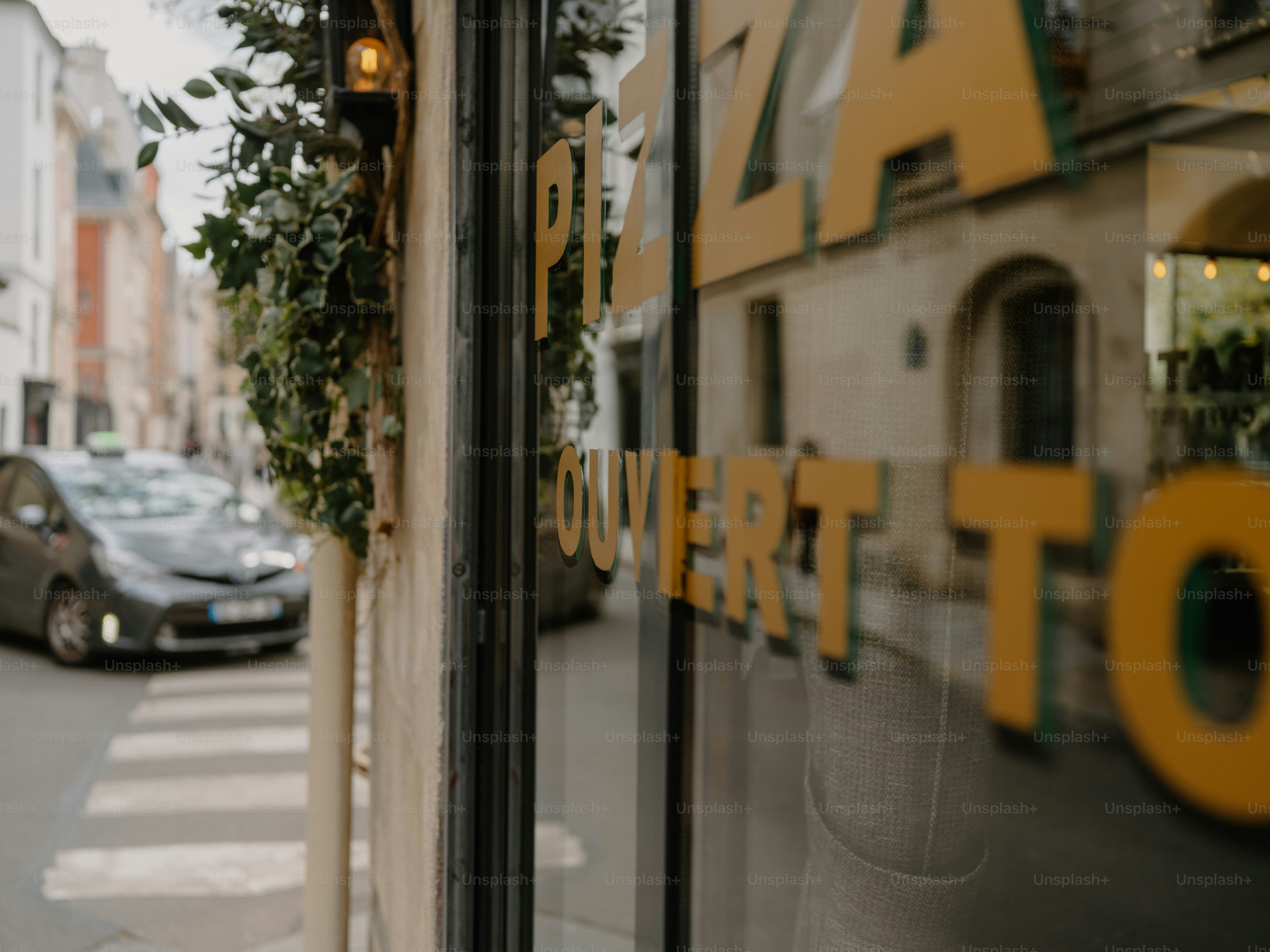 Street view of a pizza restaurant with "ouvert" sign.