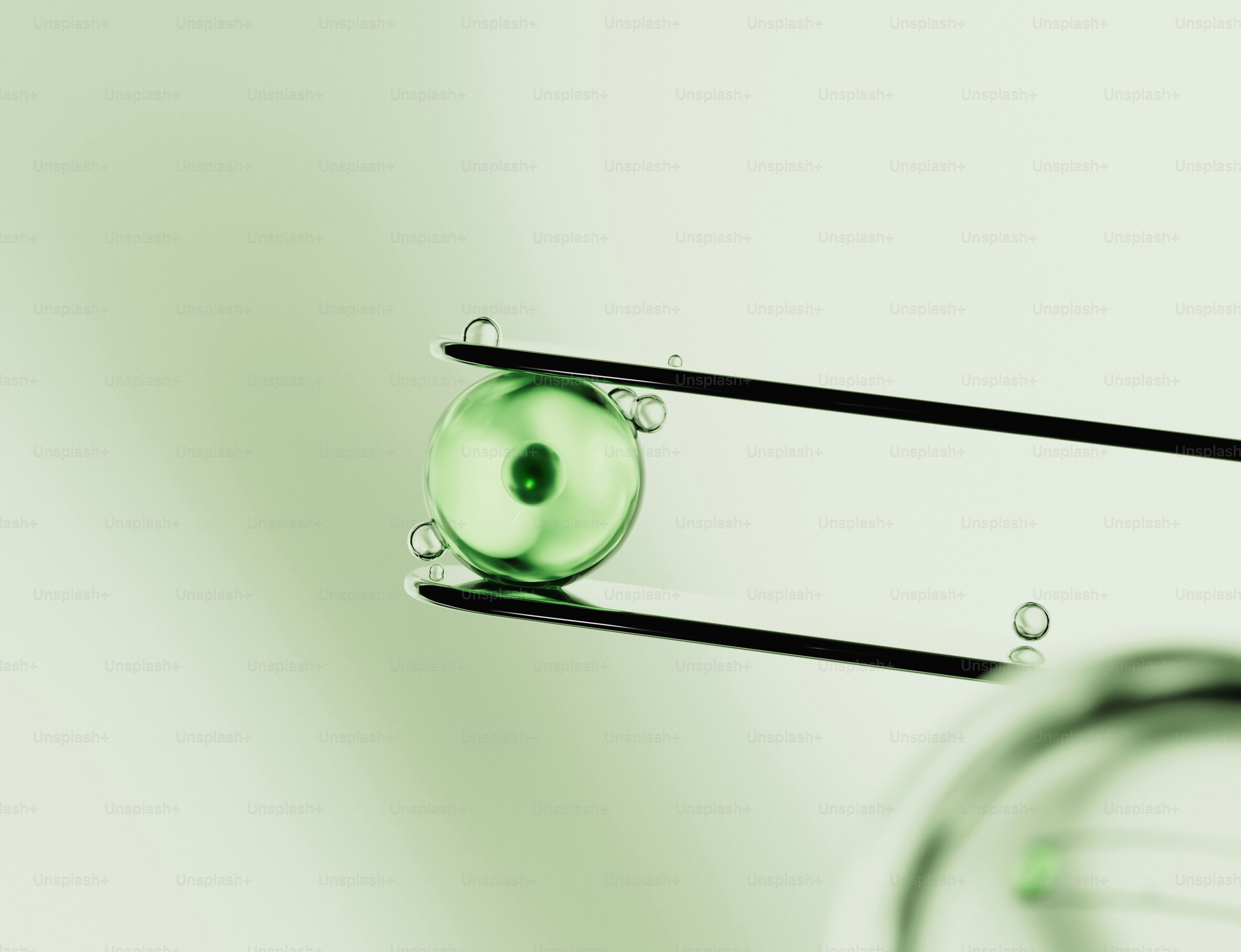 Close-up of a green glass bead held by tweezers