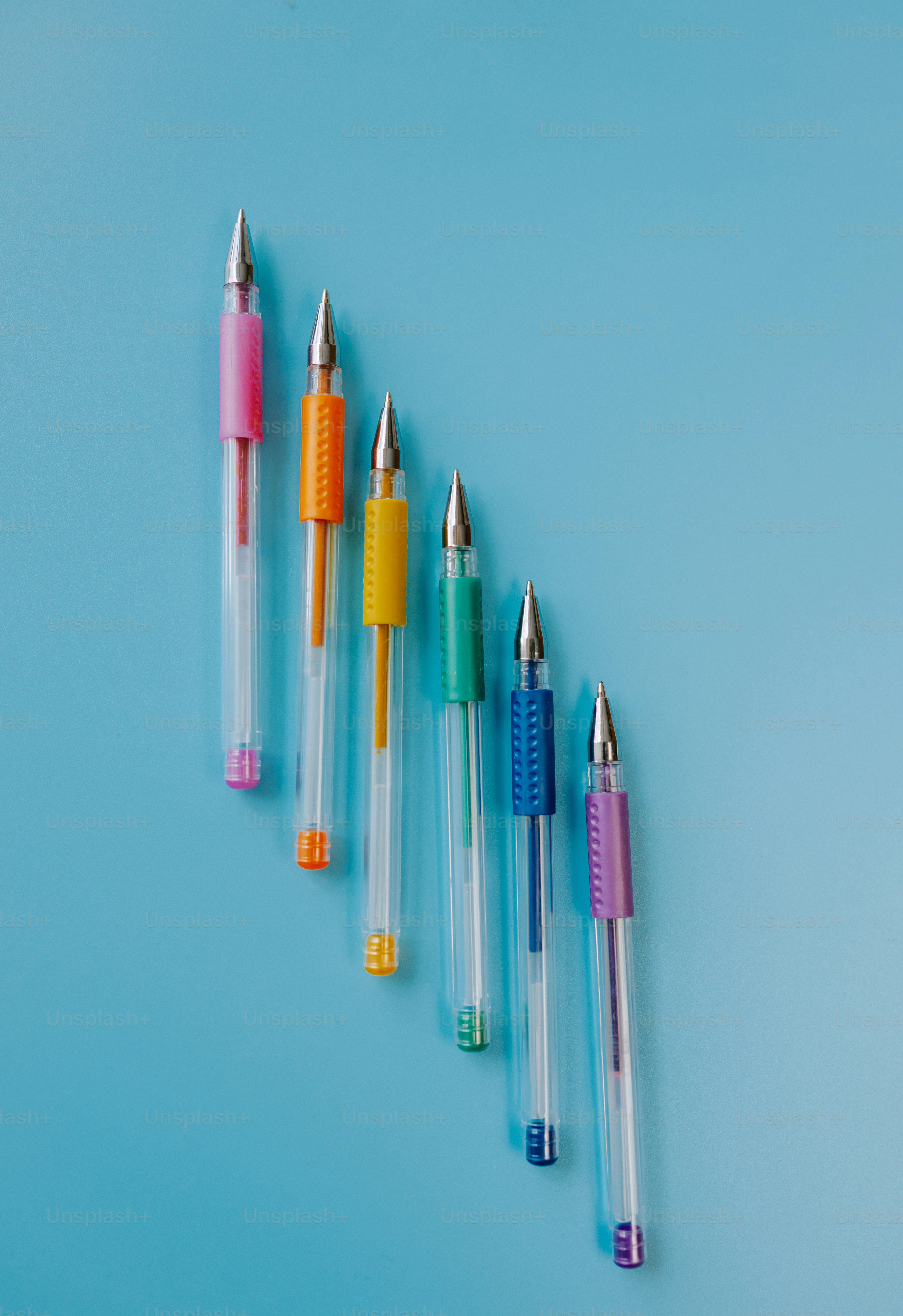 Six colorful pens arranged diagonally on a blue background
