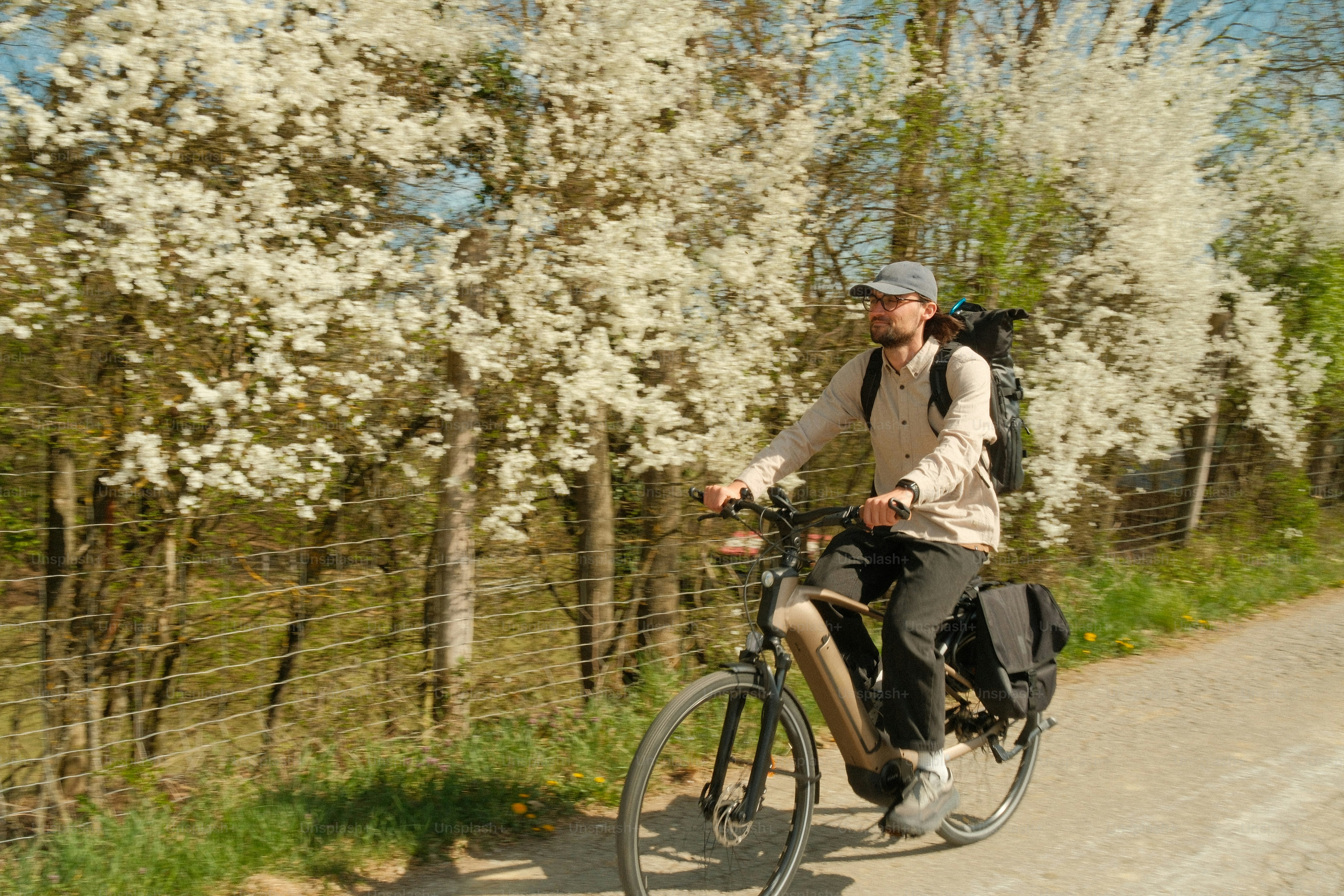 Man rides bicycle past blooming trees
