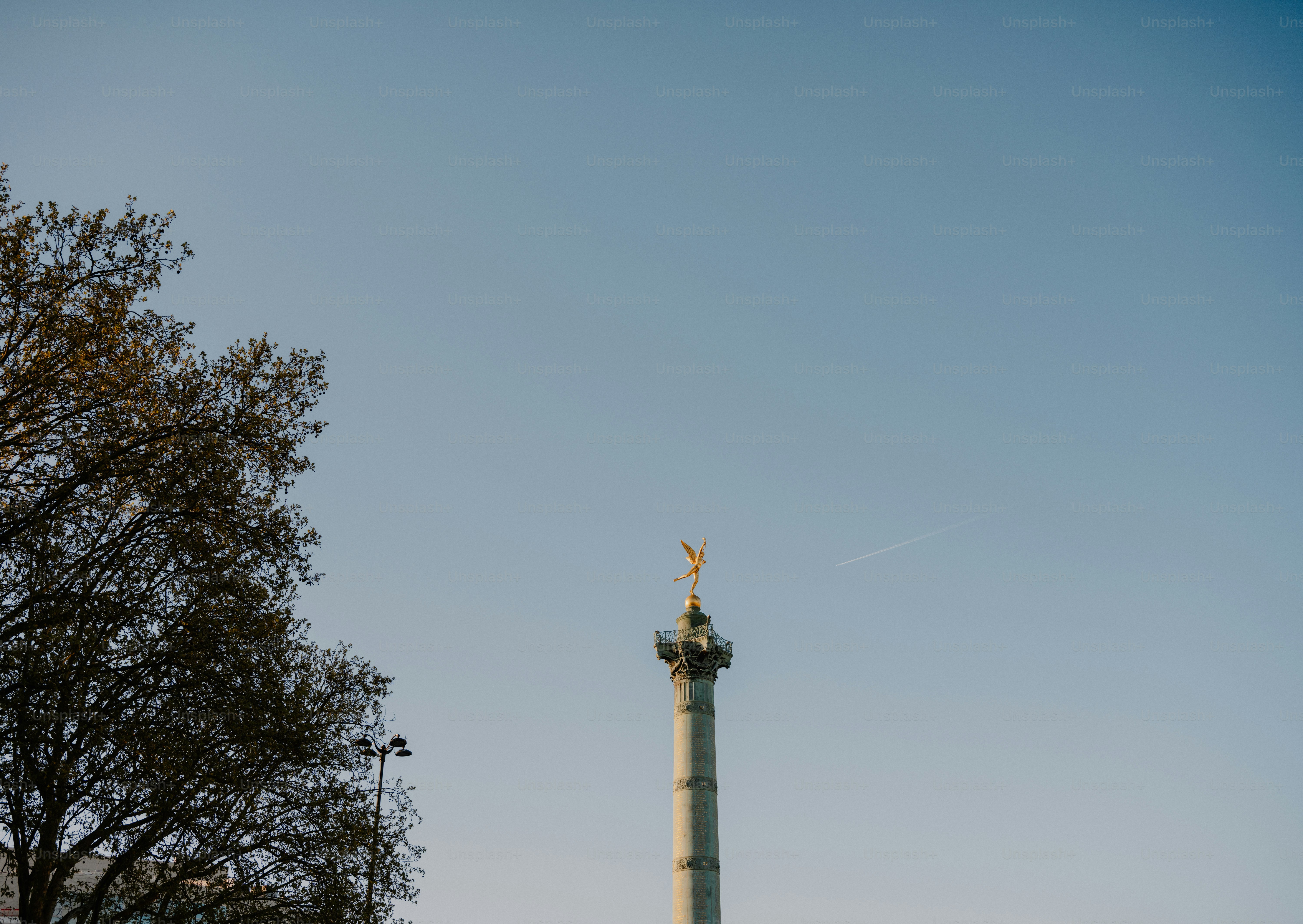 Monument de colonne avec ange doré contre ciel bleu