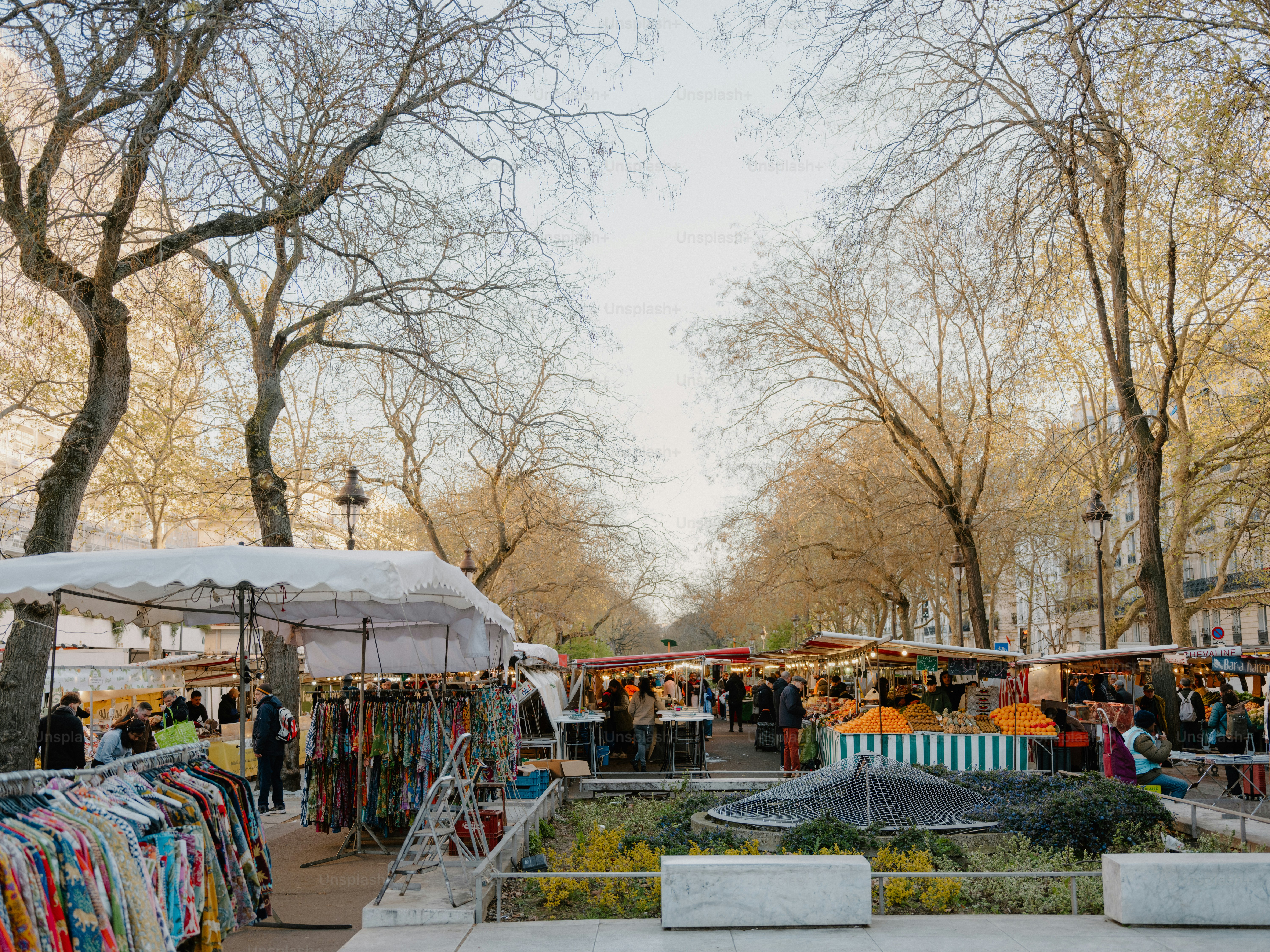 Outdoor market with stalls and trees under a bright sky