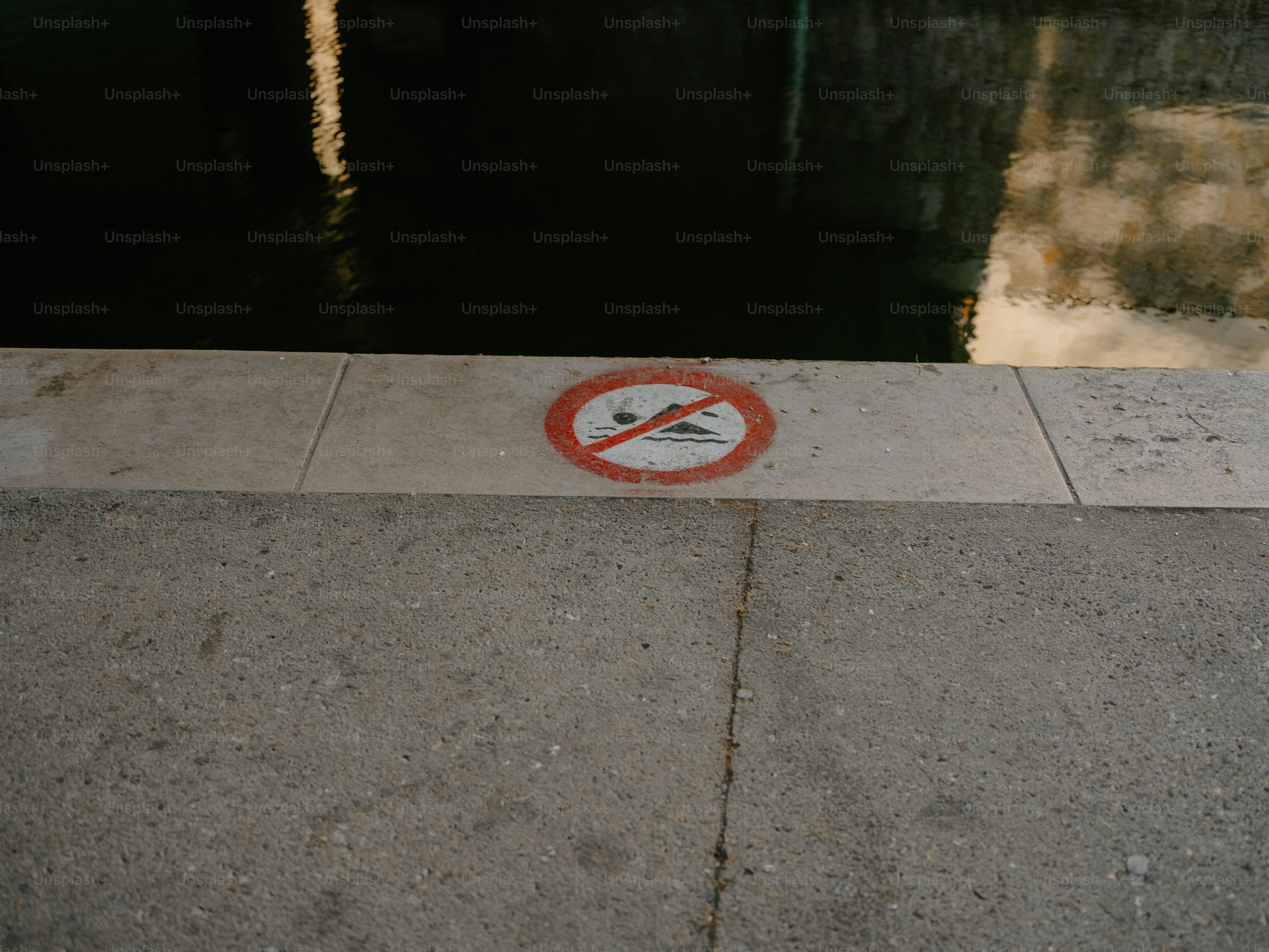 Tidak ada tanda berenang di langkan beton di tepi air.