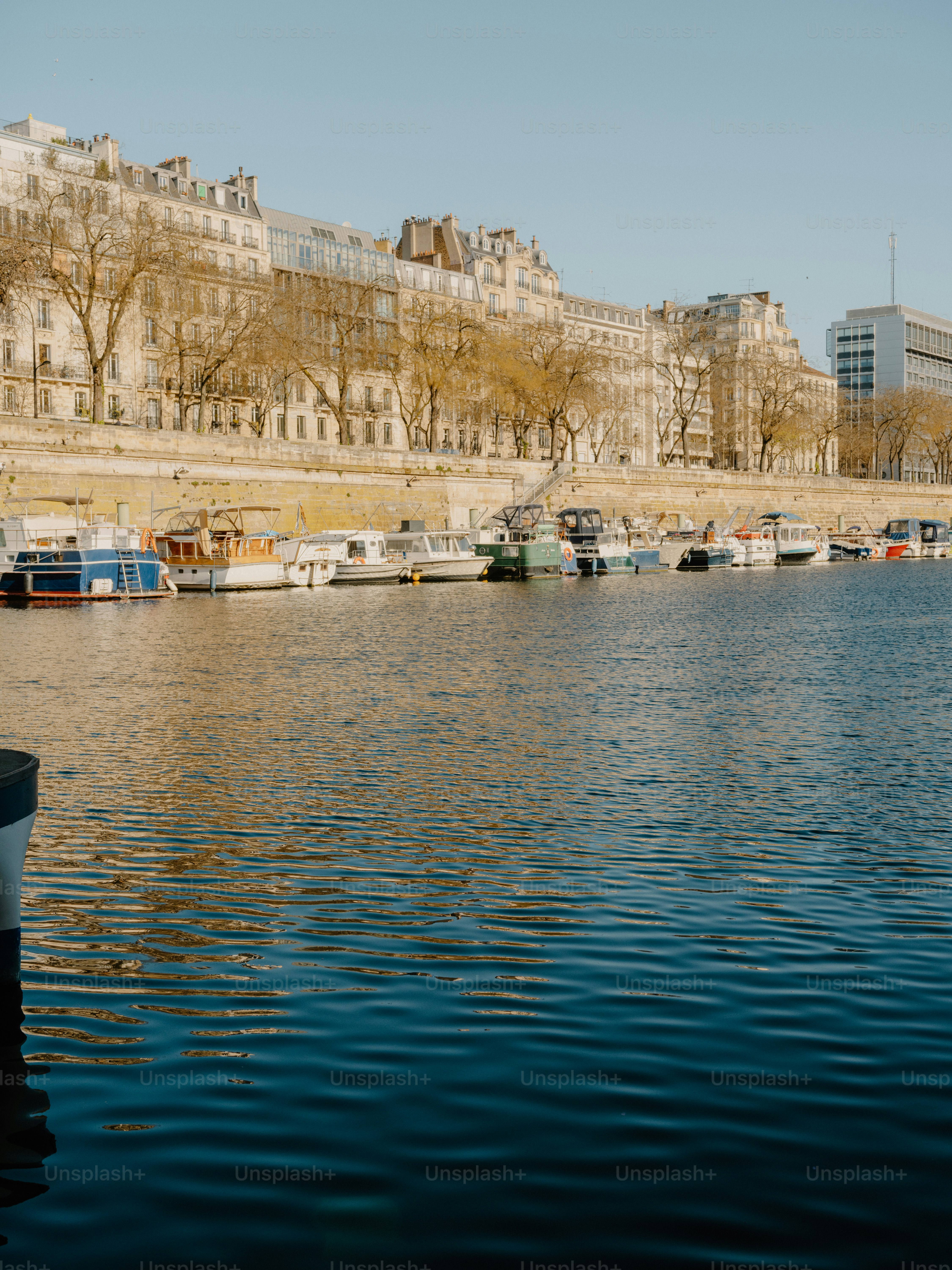 Boats docked along a river with buildings in the background.