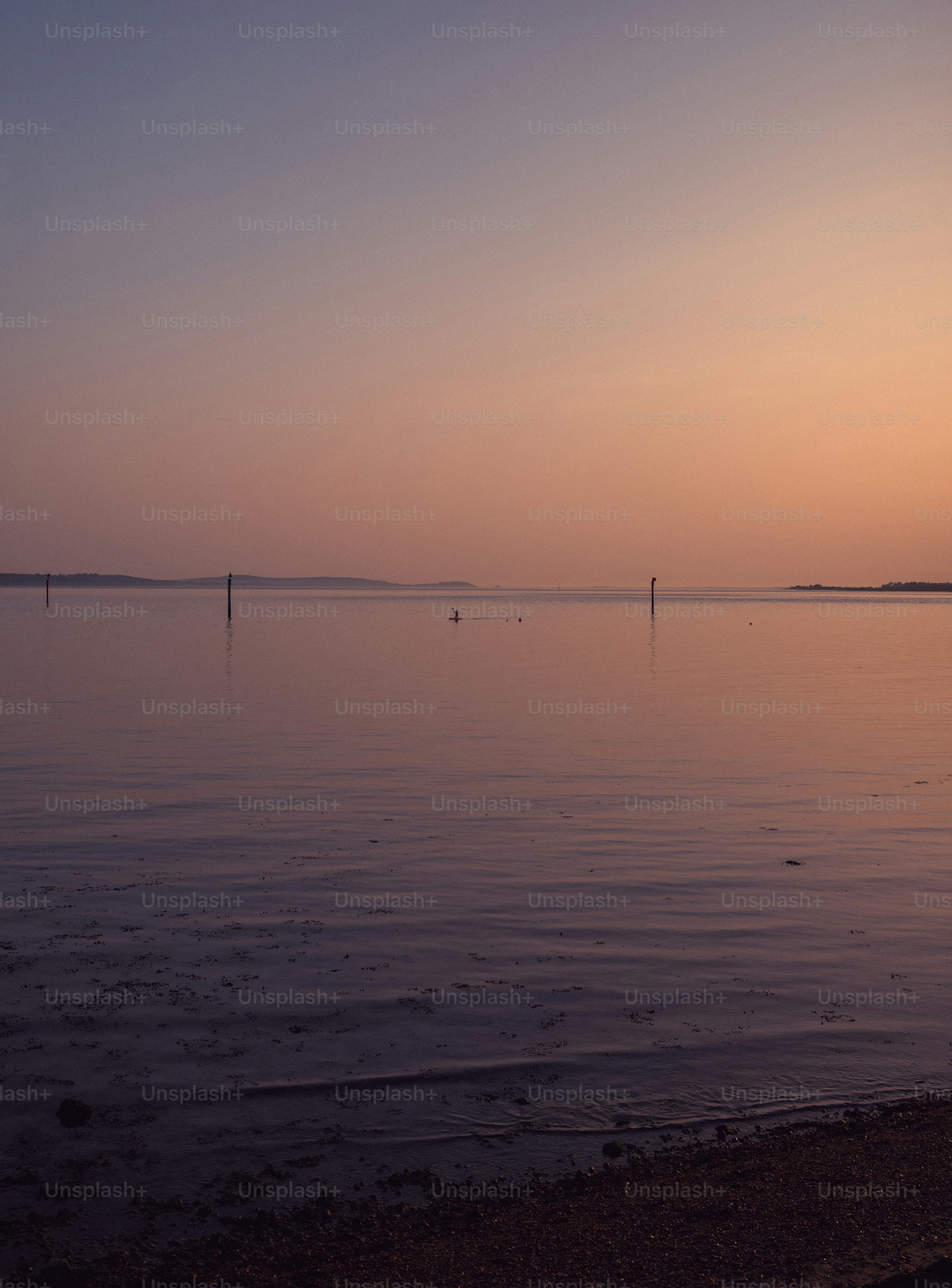 Calm water reflects a soft pastel sunset sky.