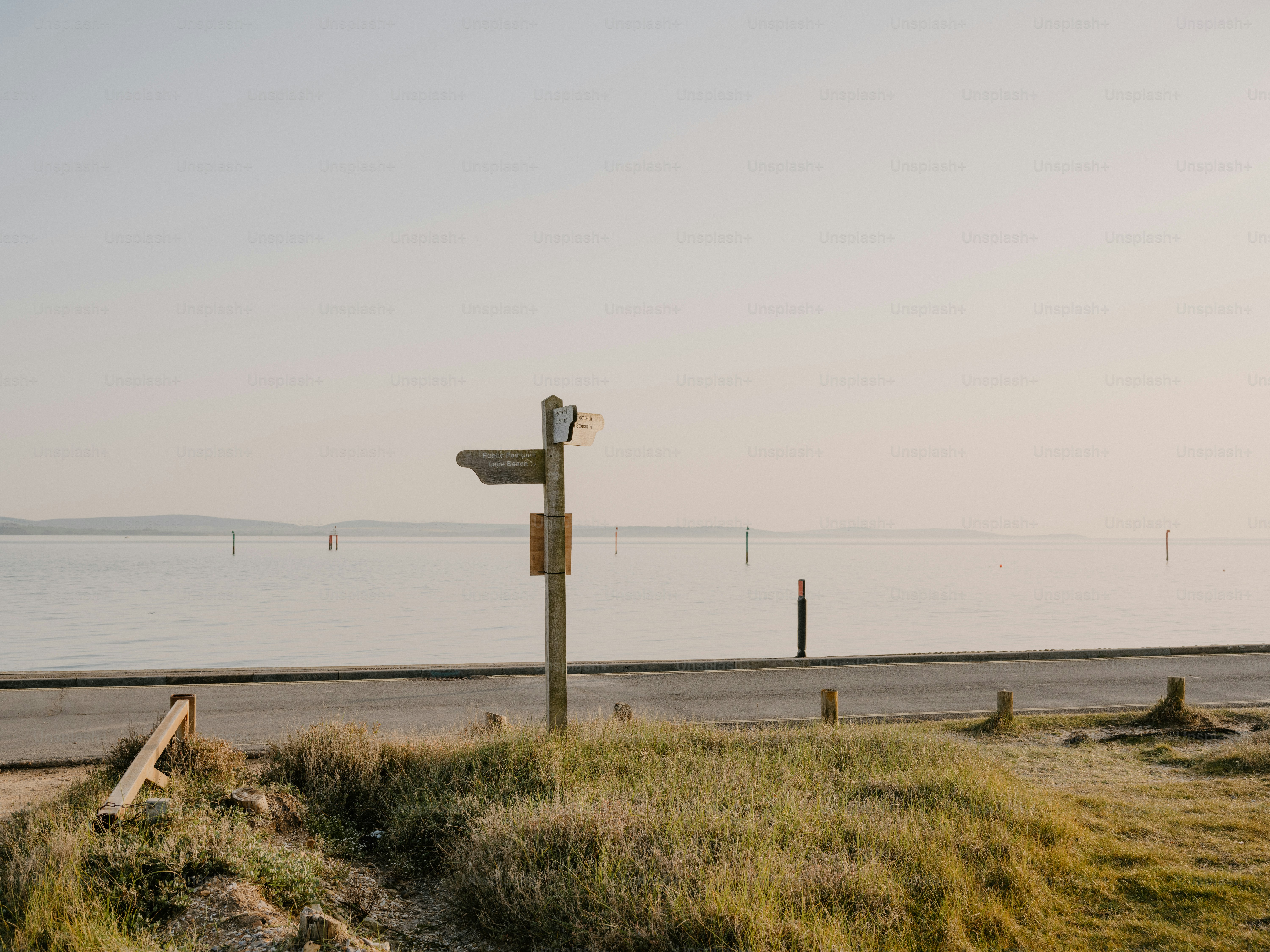 Wooden signpost by a calm body of water.