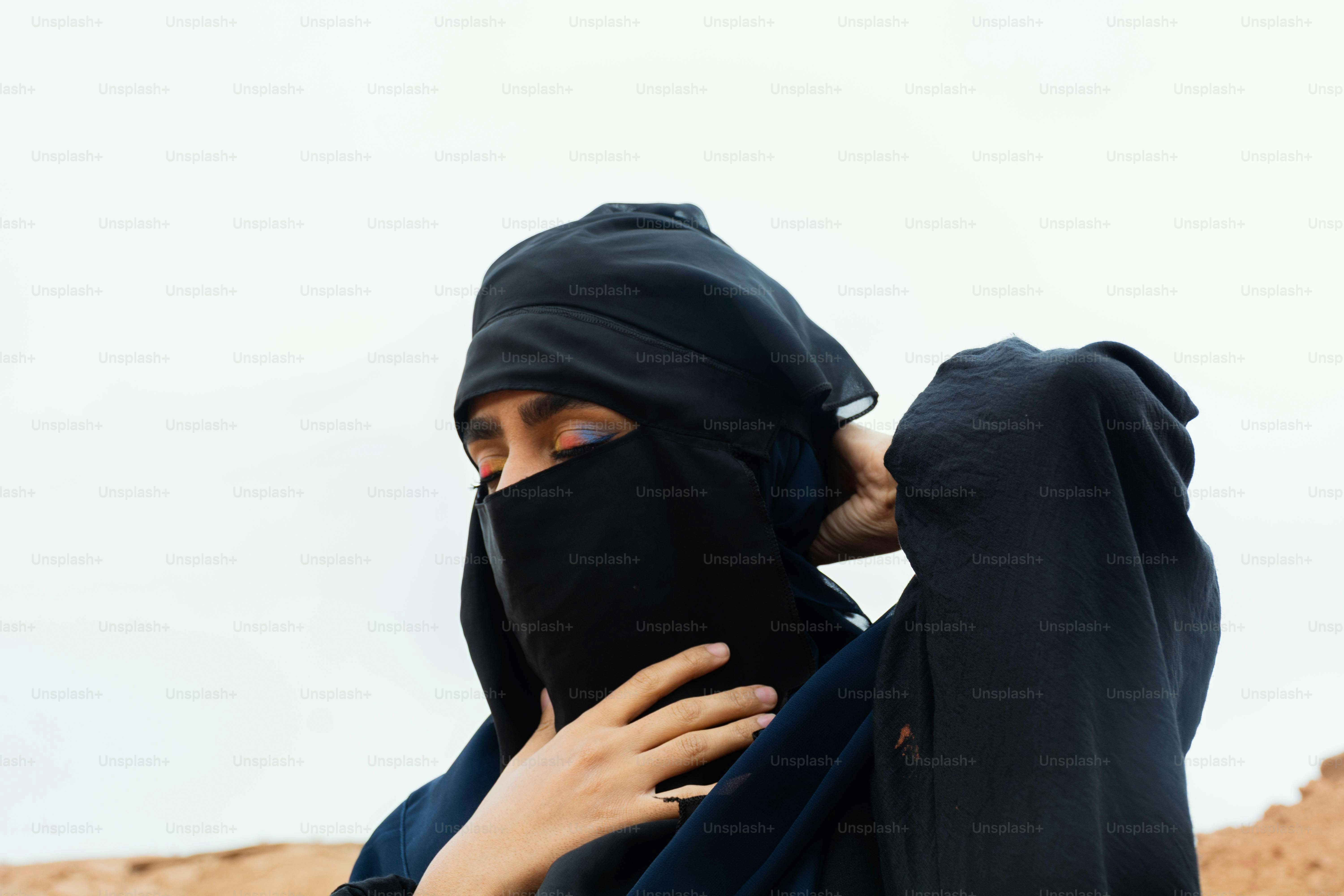 Wanita dengan pakaian islam hitam tradisional menyesuaikan cadar