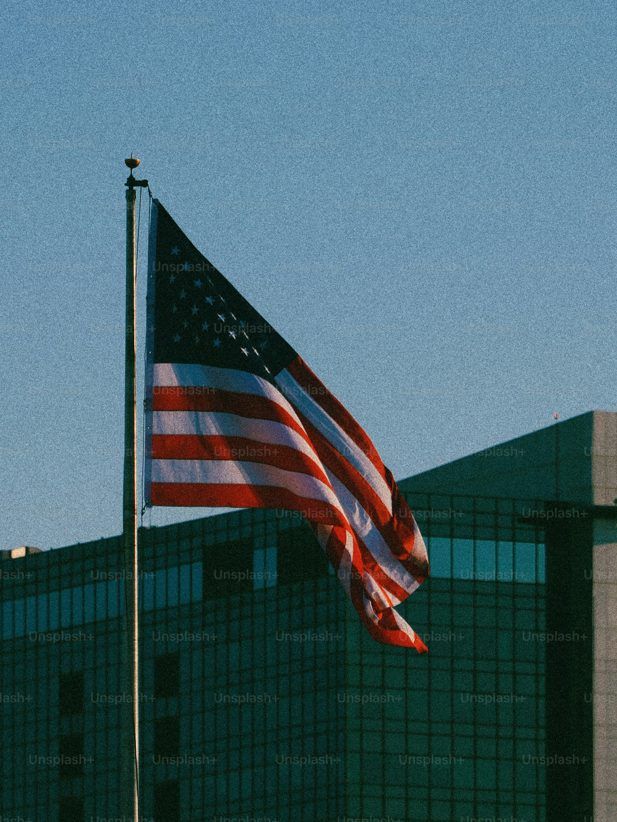 American flag waving against a clear blue sky.