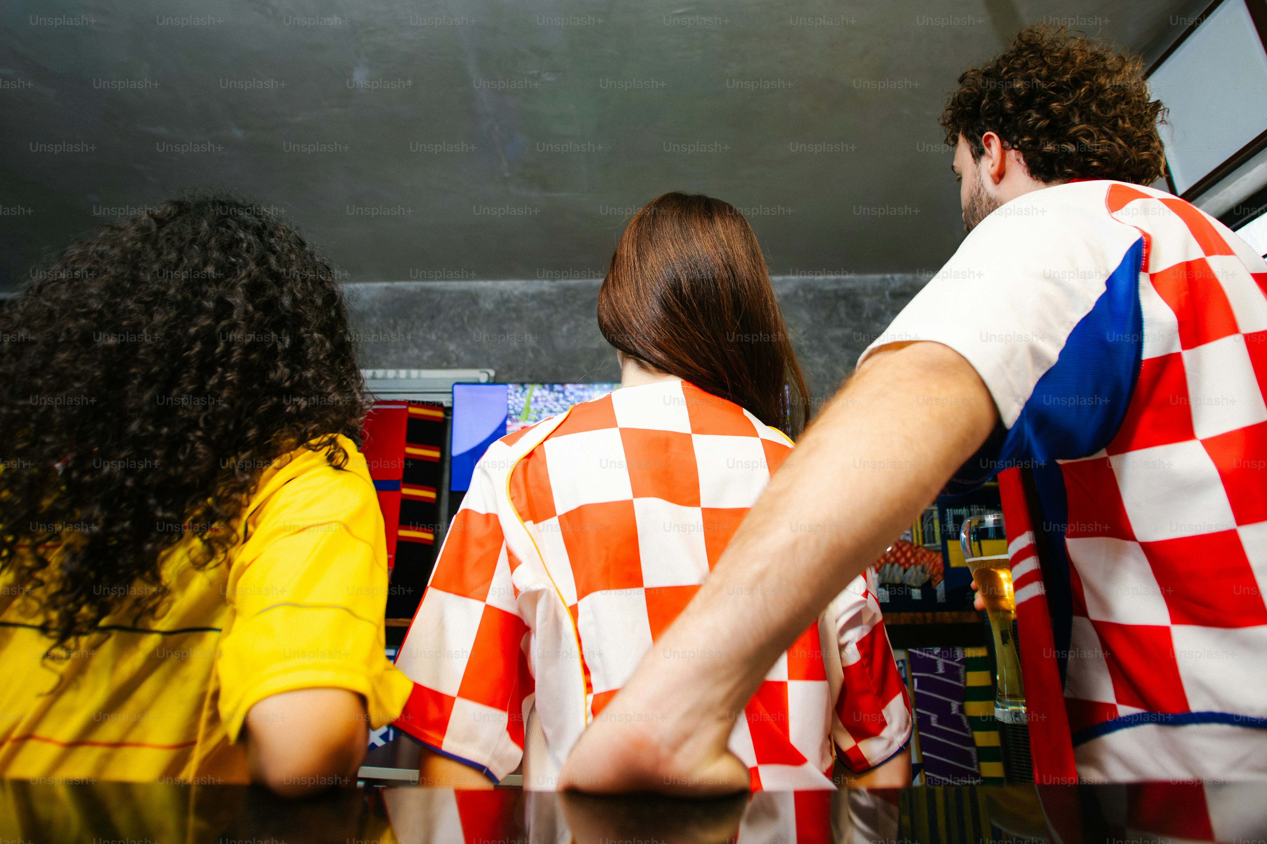 Tre persone che guardano la televisione con camicie a quadri.